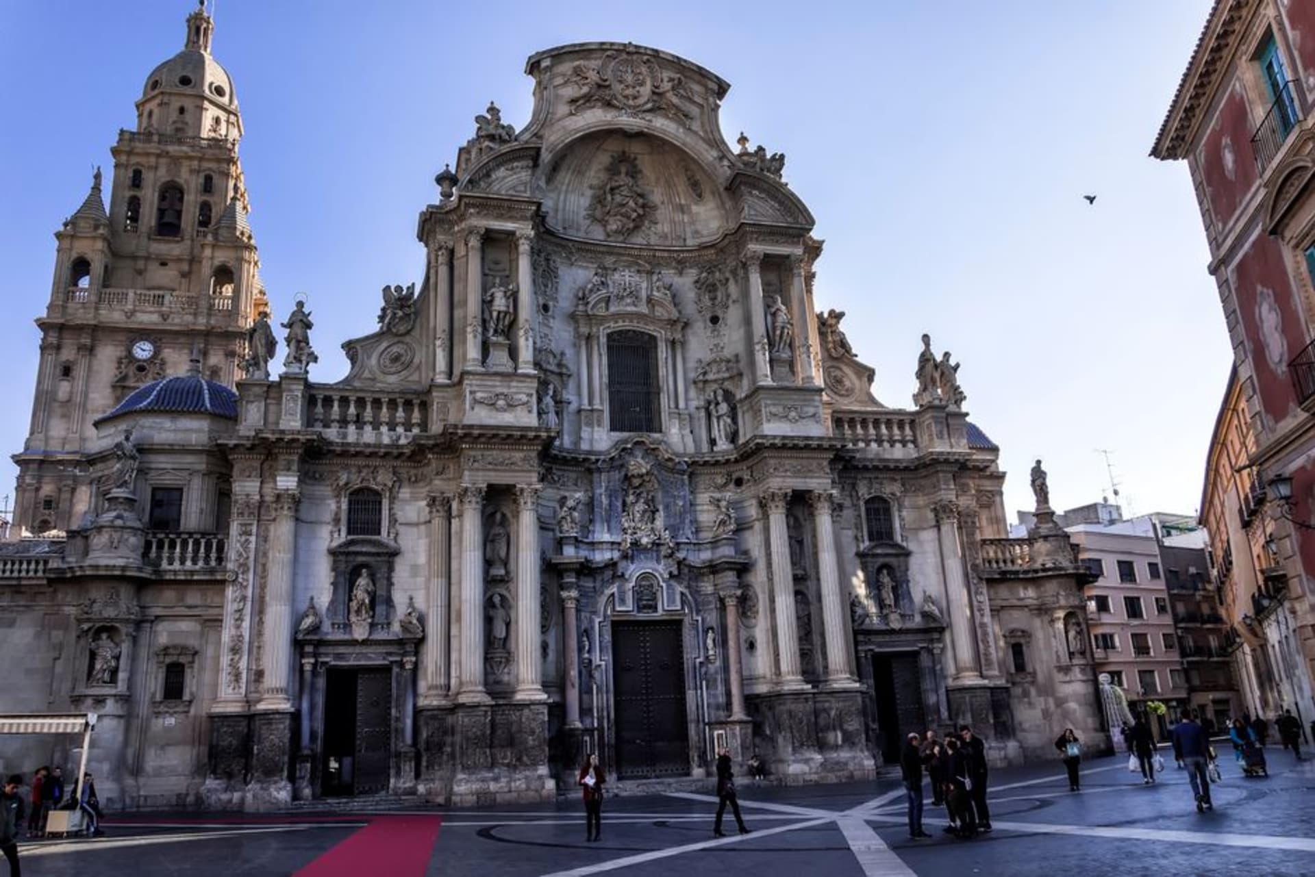 Murcia Cathedral's ornate baroque facade rising over the Plaza de la Cruz with palm trees in the foreground
