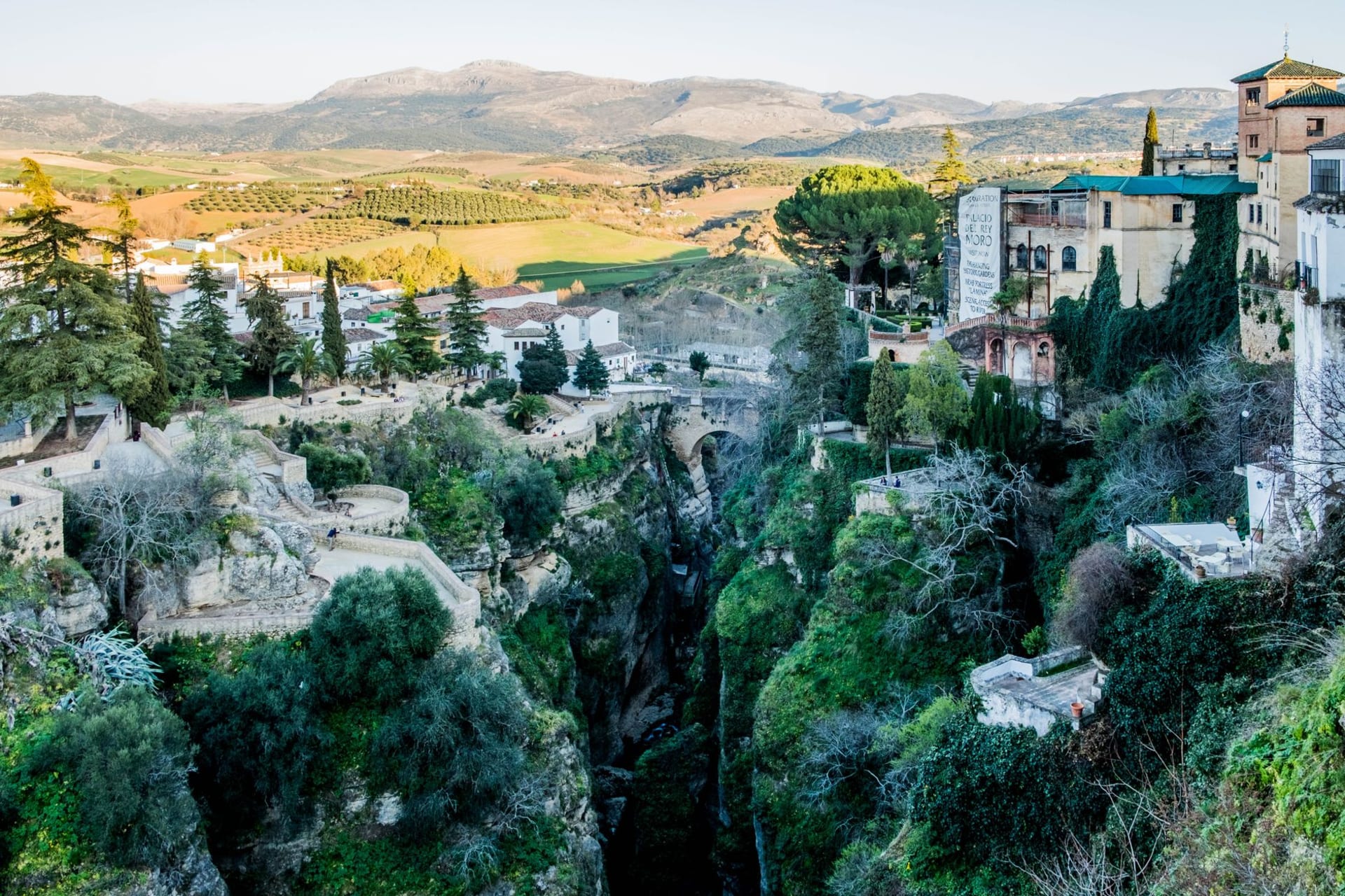 The Puente Nuevo bridge arching over the deep El Tajo gorge in Ronda, white buildings crowding the cliff edge beneath a wide Andalusian sky