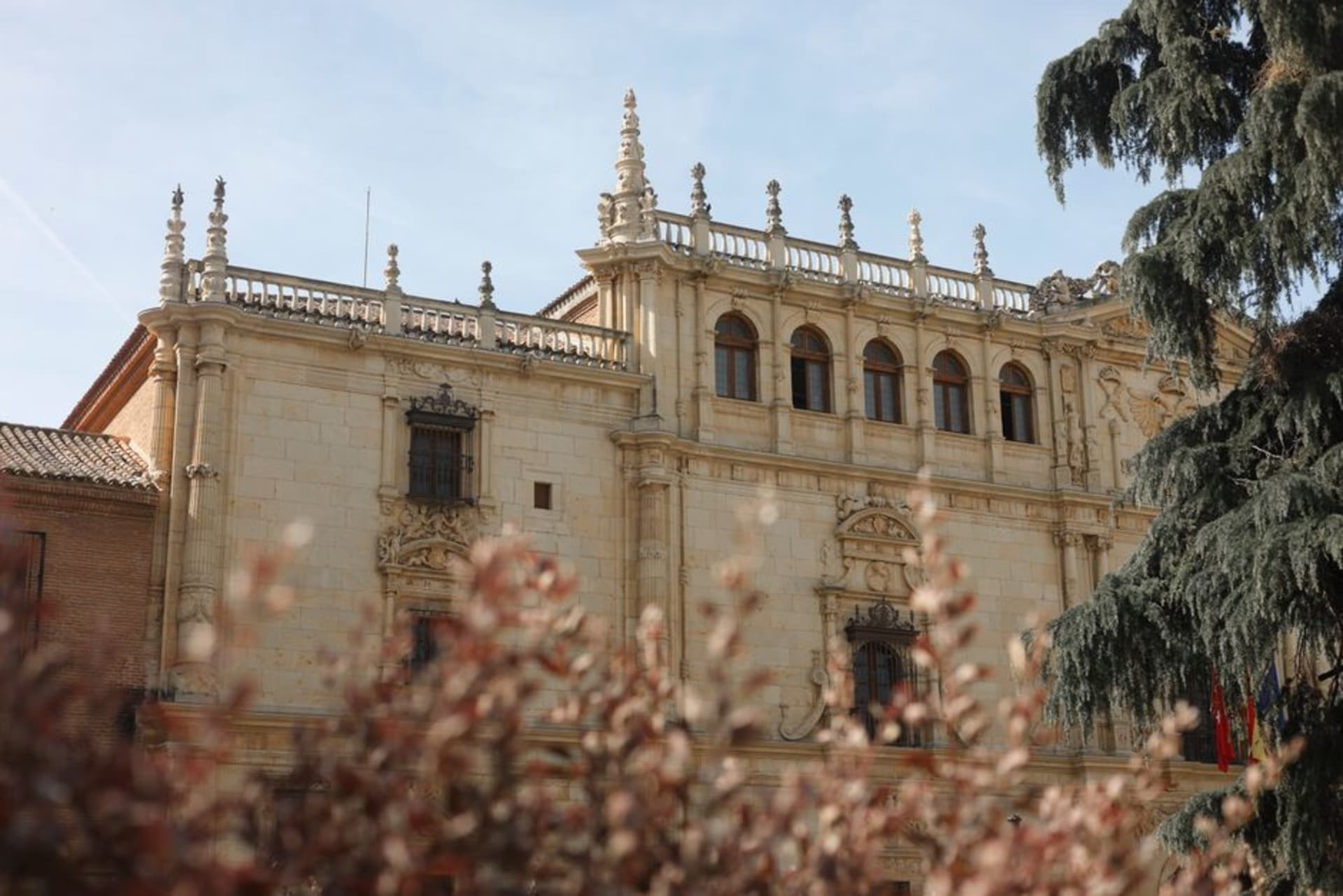 The historic university buildings of Alcalá de Henares along a stone plaza at golden hour