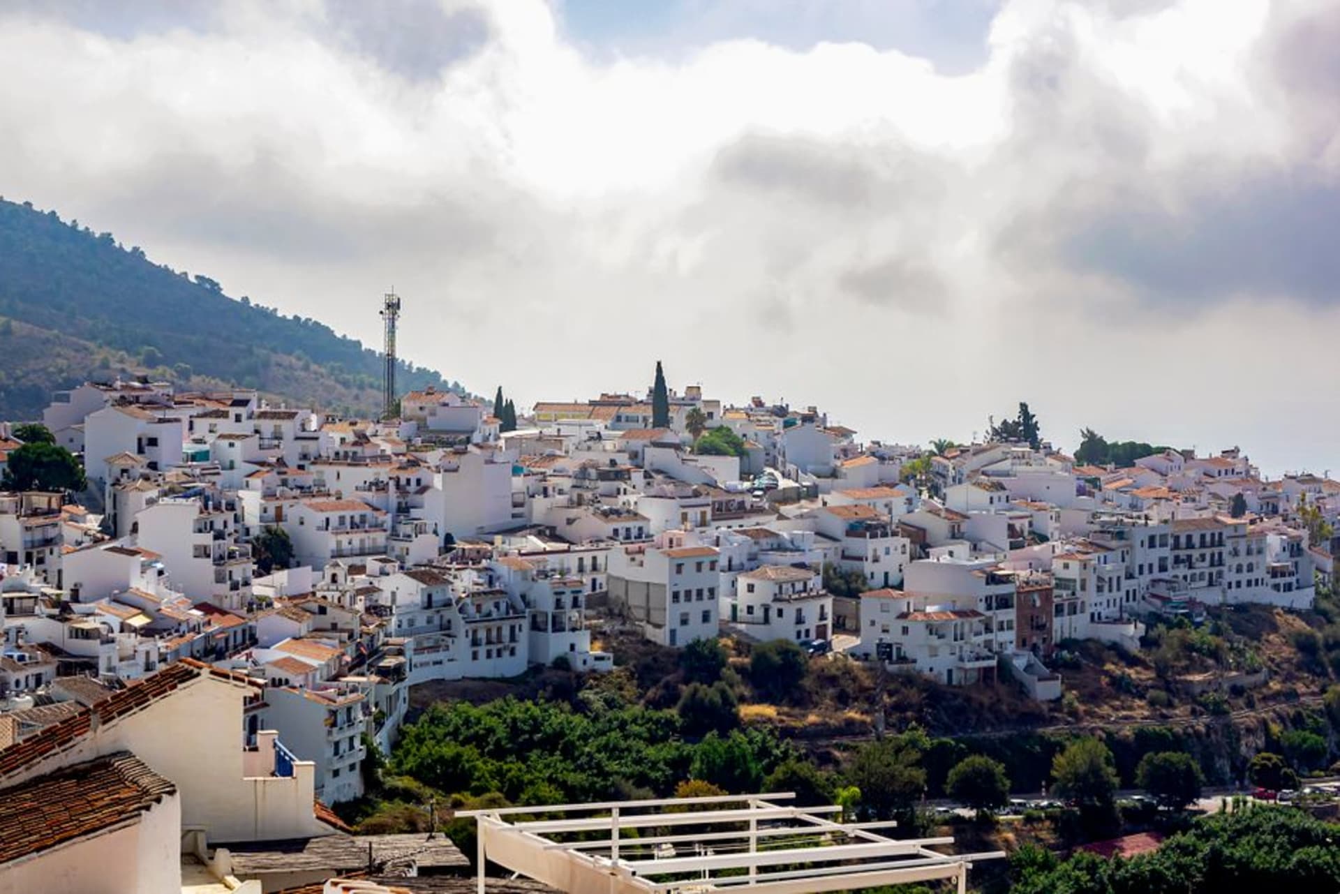 Frigiliana's whitewashed old town climbing the hillside above Nerja, with the Sierra de Almijara mountains rising behind