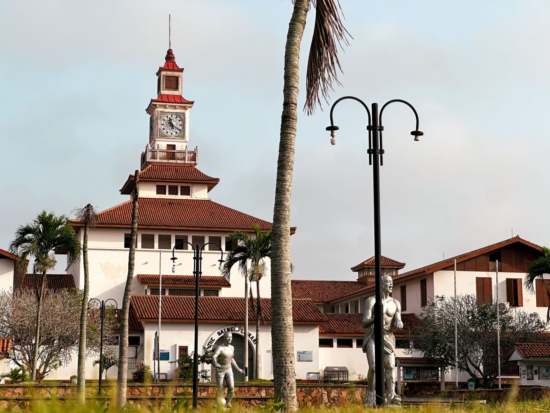 Pale yellow Dutch colonial wooden townhouses lining a wide riverside boulevard in Paramaribo, with a blue sky reflected in the Suriname River behind them