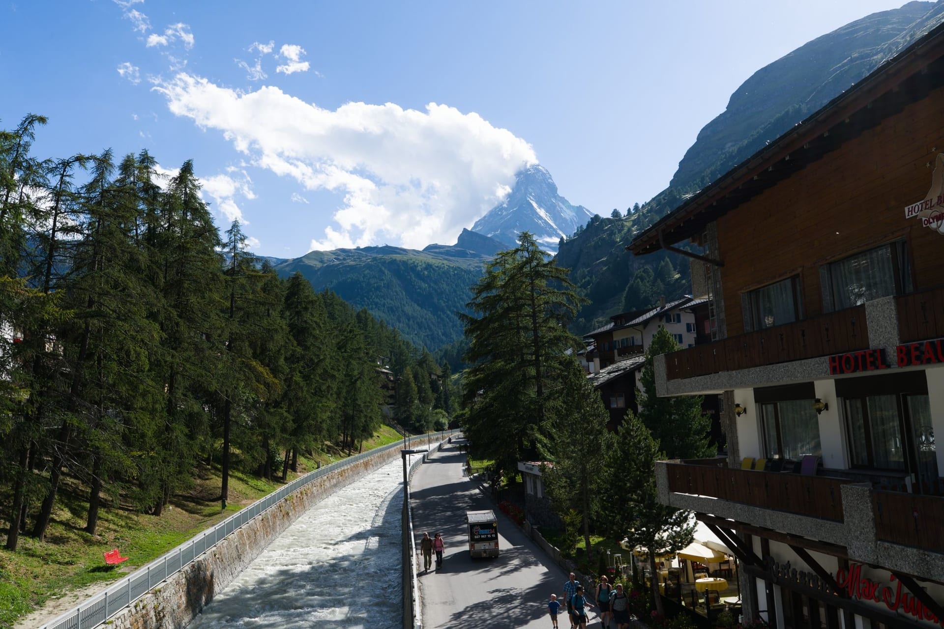 The Matterhorn rising sharply above Zermatt's snow-covered rooftops and timber chalets at dusk, the sky turning deep violet behind the peak