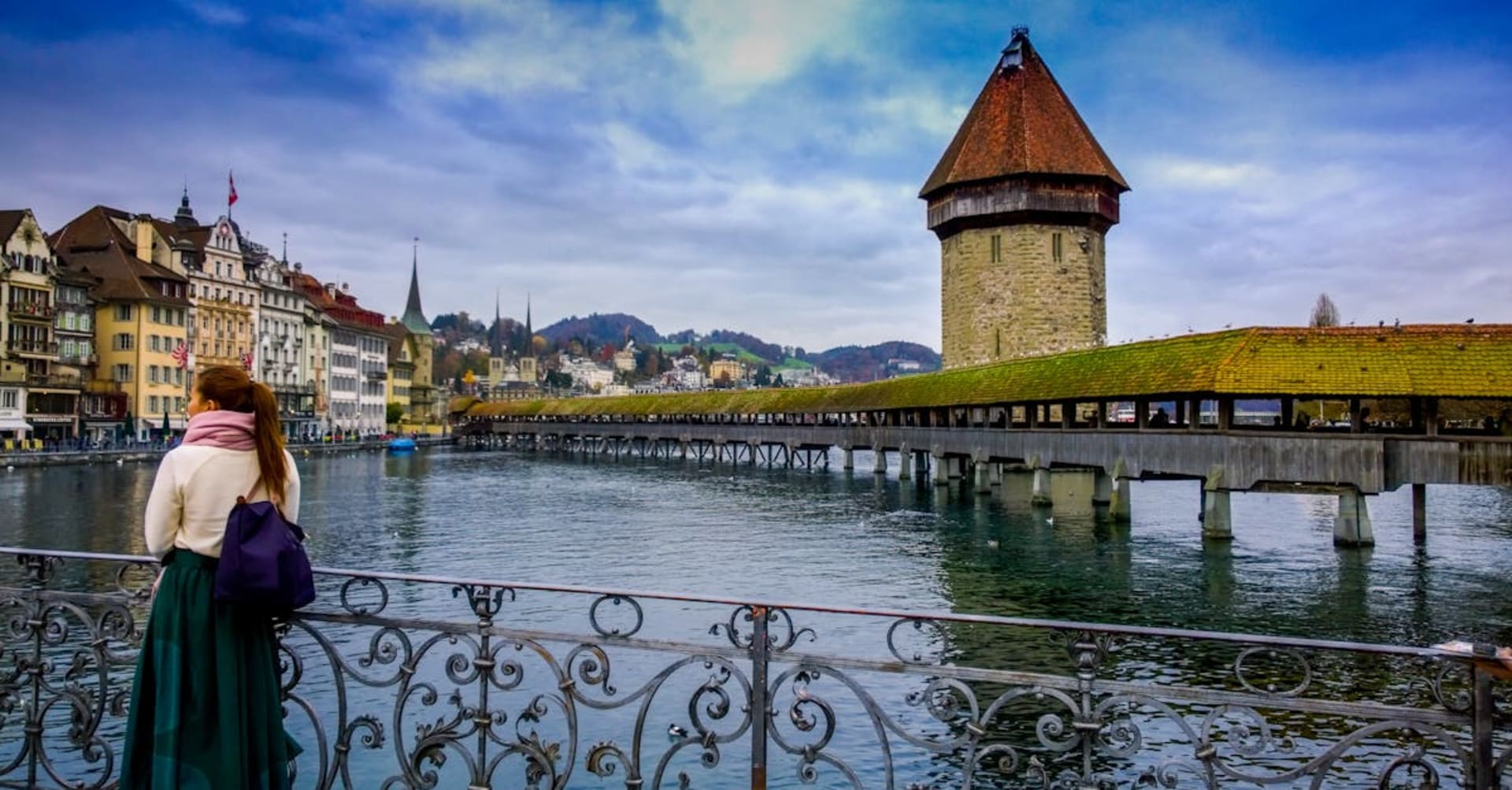The Chapel Bridge and Water Tower reflected in Lake Lucerne with mountains behind