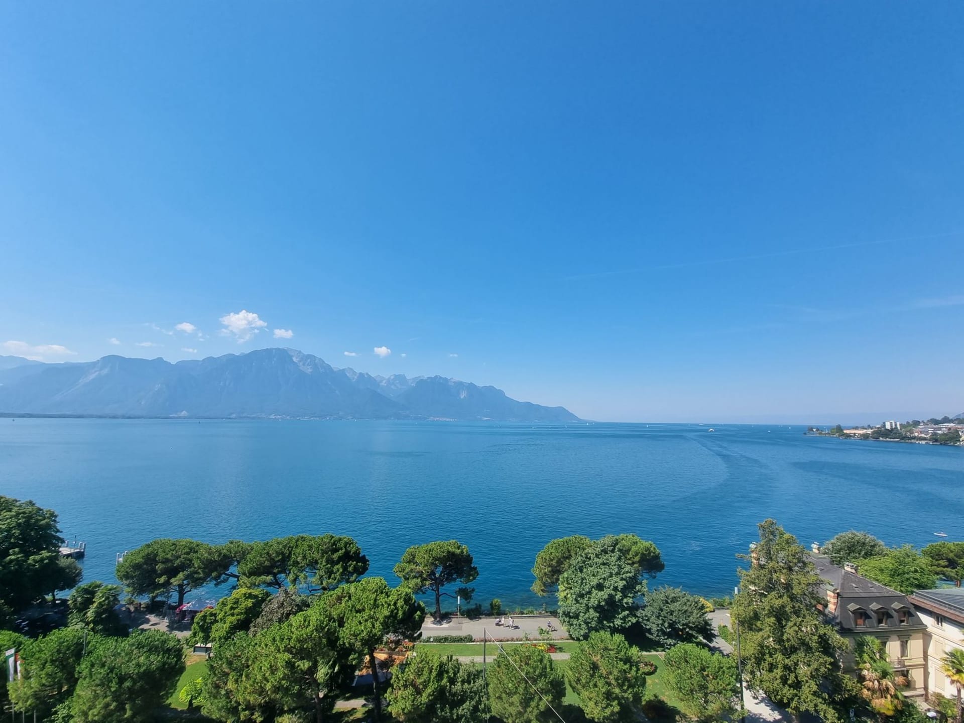 The lakeside promenade of Montreux with flowers, palms and mountains across Lake Geneva