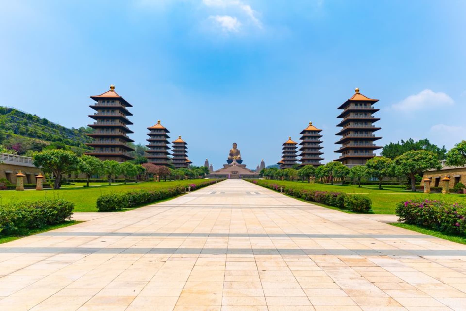 A colossal golden seated Buddha statue rising above the Fo Guang Shan monastery grounds, flanked by rows of smaller golden figures.