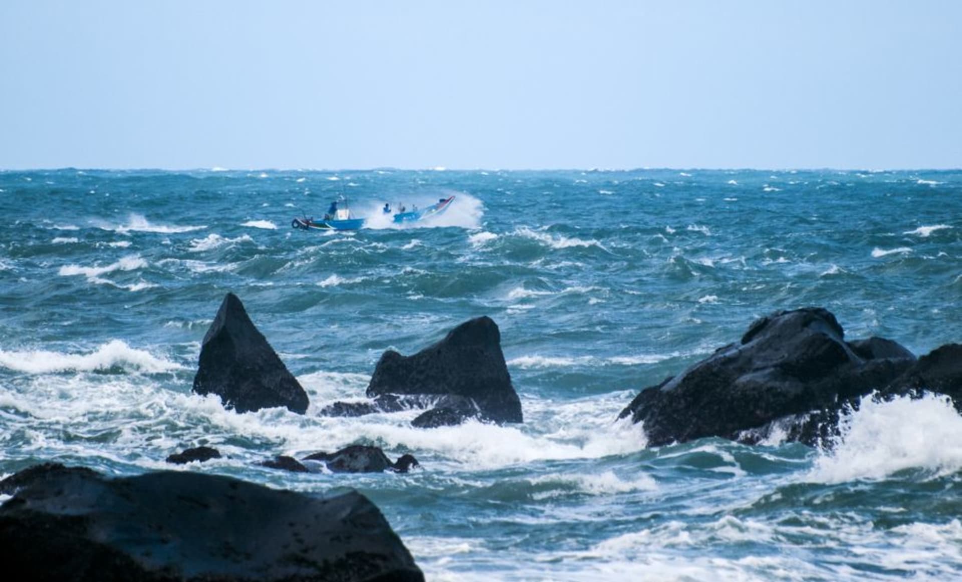 Alta formación rocosa triangular de piedra caliza que se asemeja a un barco de vela emergiendo de aguas costeras poco profundas cerca de Kenting, Taiwán