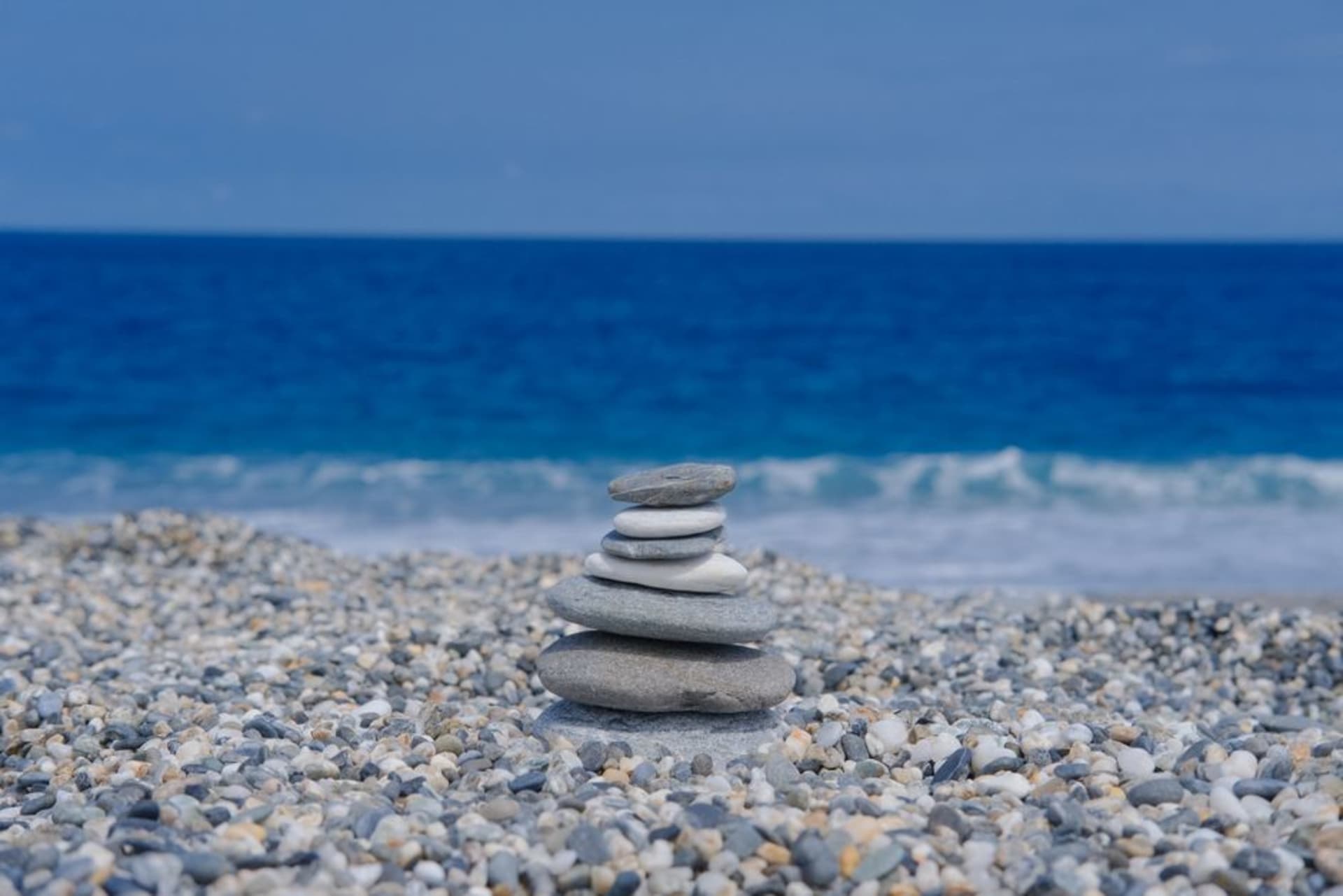 Smooth grey pebbles on the crescent-shaped shore of Qixingtan Beach with mountains rising behind and waves rolling in from the Pacific