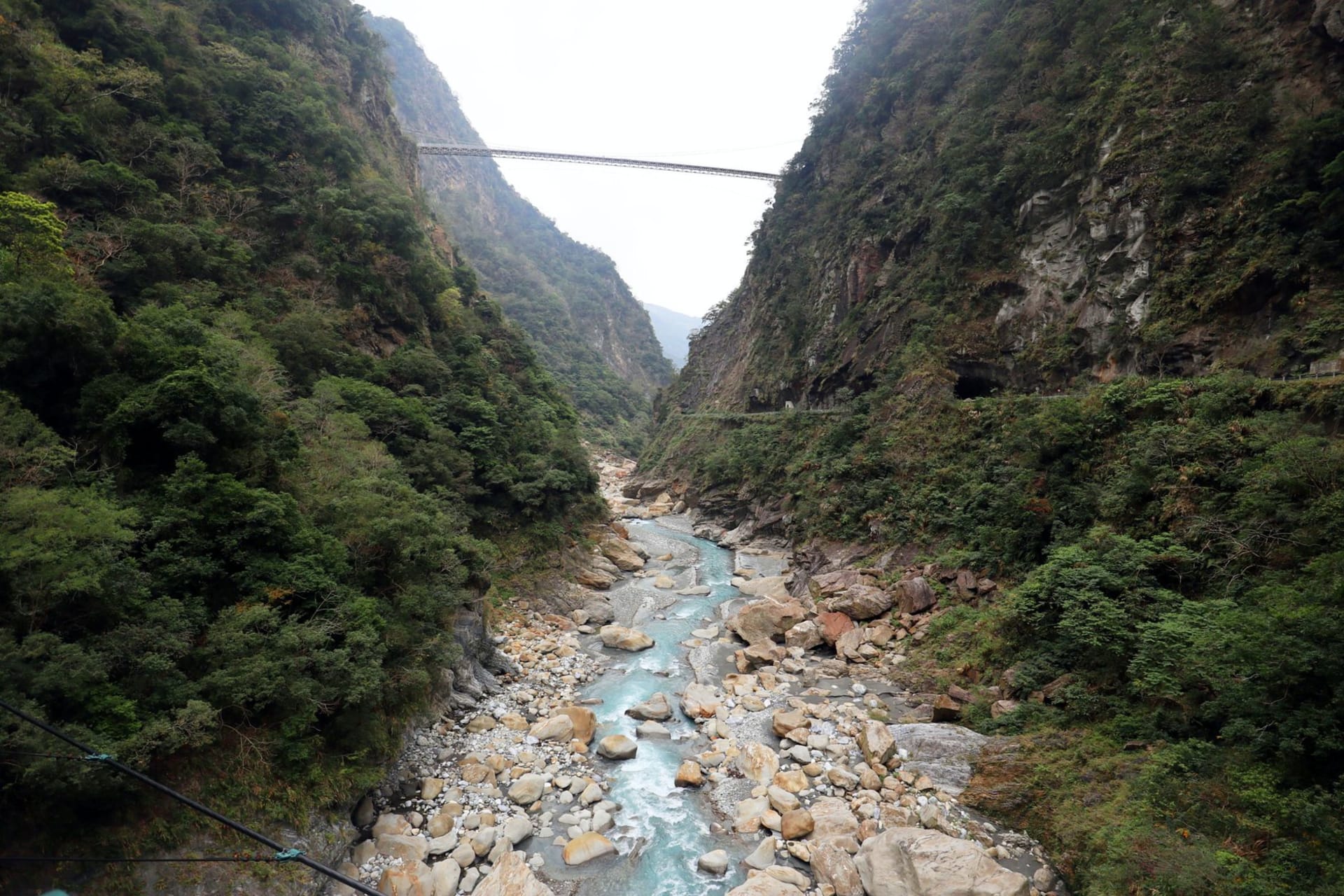 Panoramic view of a bridge spanning a river winding through the steep green cliffs of Taroko Gorge, Taiwan
