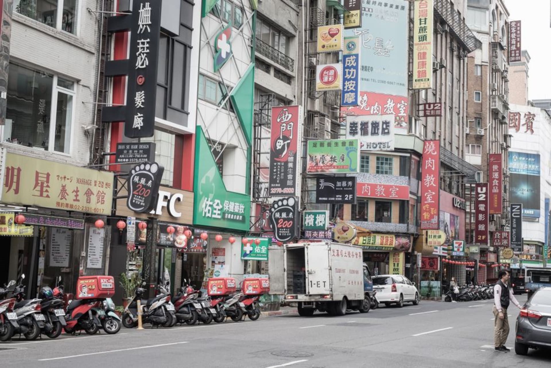 Neon shop signs and crowds filling the pedestrian streets of Ximending at night, storefronts stacked with Japanese and Taiwanese streetwear brands