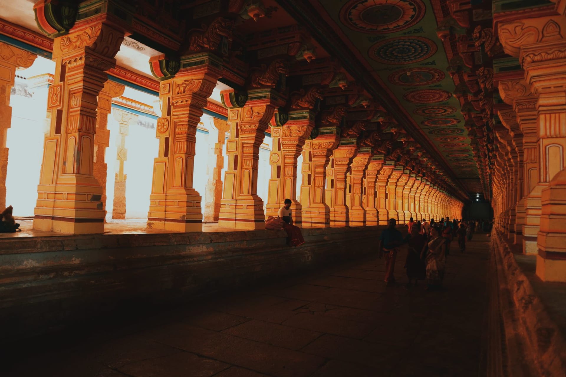The soaring multi-colored gopurams of Meenakshi Amman Temple rising above the city at golden hour, intricate sculptures covering every surface