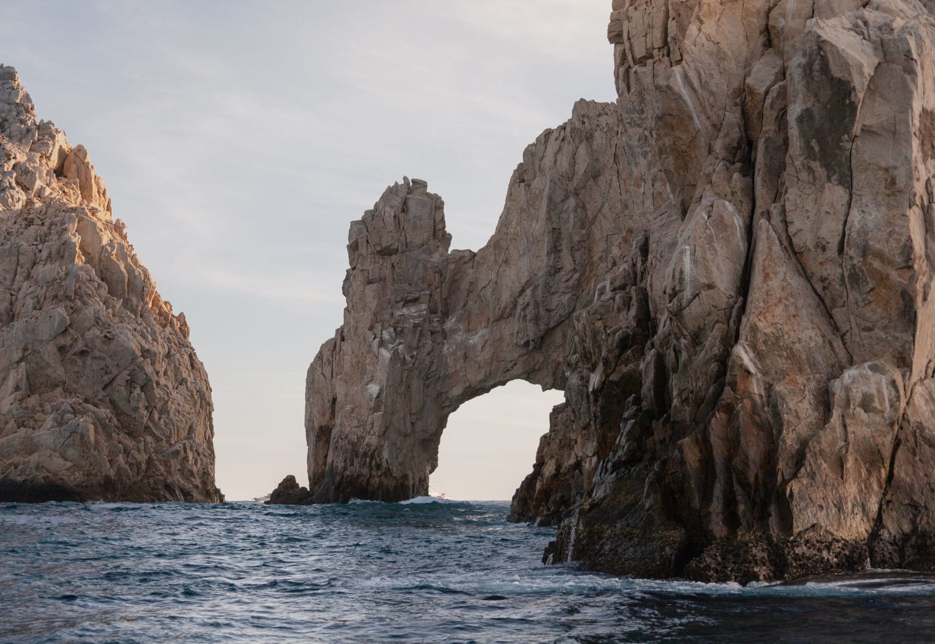 Aerial view of Cabo San Juan's twin beaches separated by a jungle-covered rocky point under heavy Caribbean light