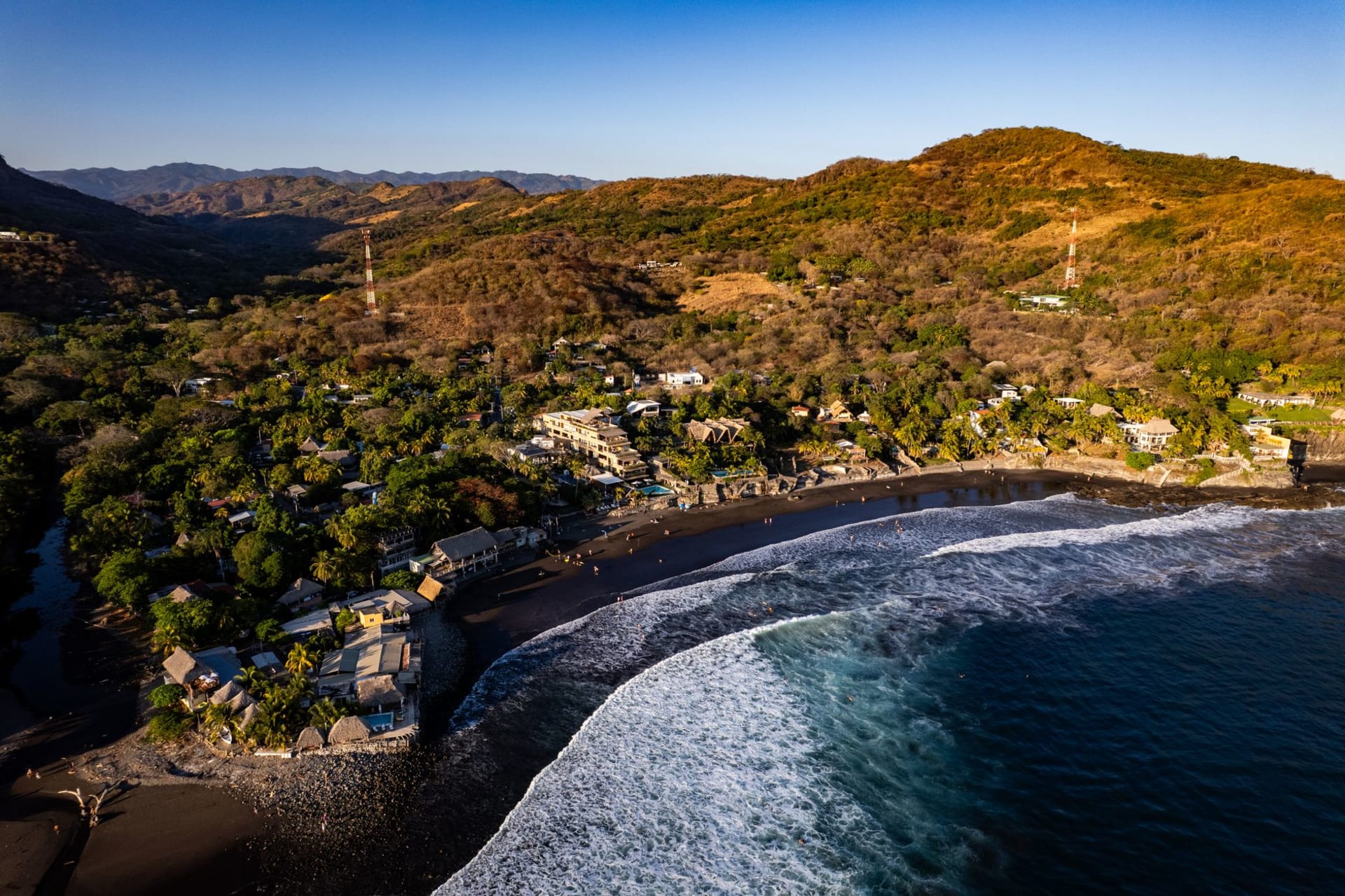 Circular stone terraces of El Pueblito rising through dense jungle, Caribbean coastline visible in the far distance through the canopy