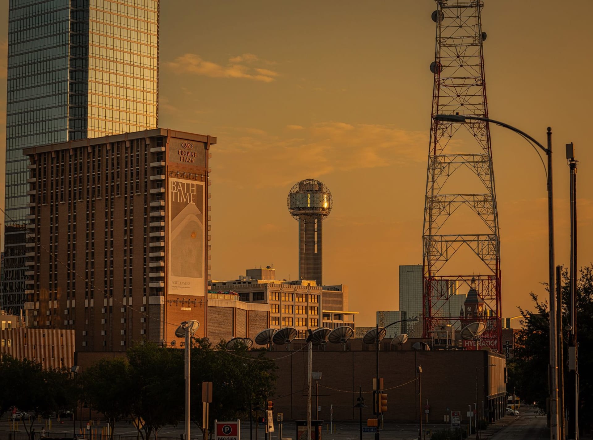 The Dallas Arts District at dusk, the Winspear Opera House's red lattice canopy glowing against a deep blue Texas sky, Calatrava's bridge visible in the distance