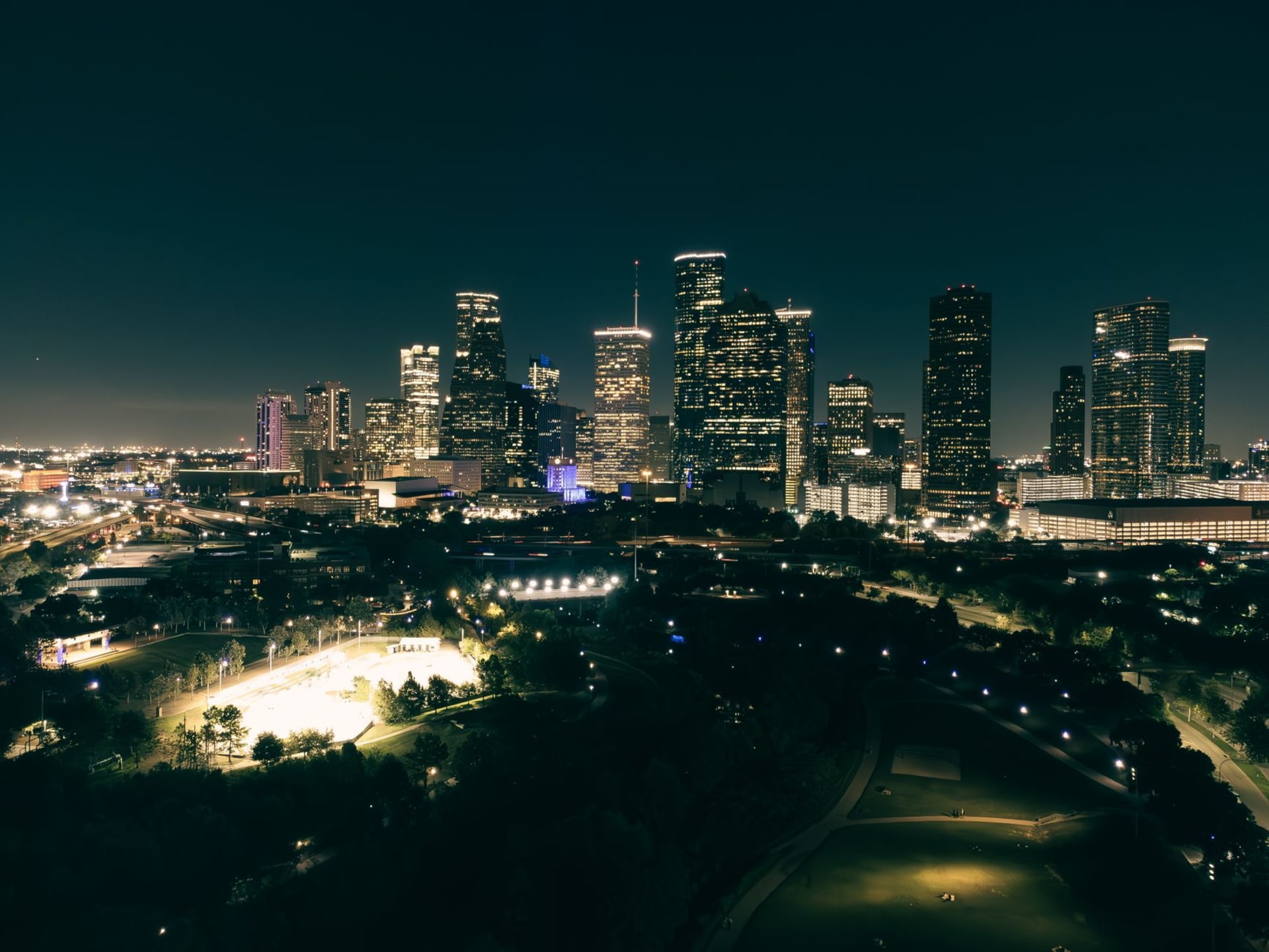 Houston's downtown skyline reflected in Buffalo Bayou at blue hour, joggers and cyclists on the bayou trail below