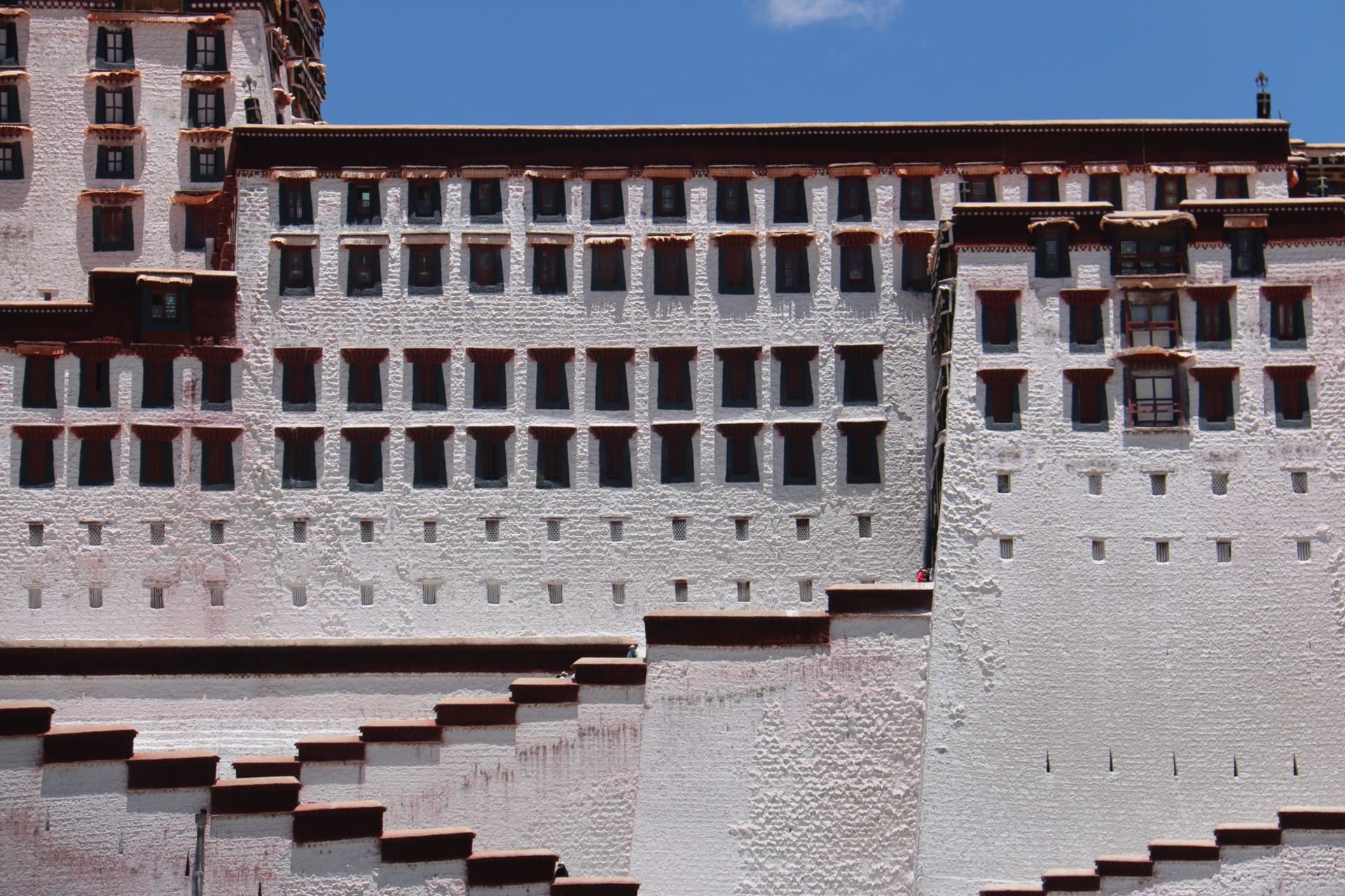 The white and ochre Potala Palace rising above Lhasa's rooftops against a deep blue high-altitude sky