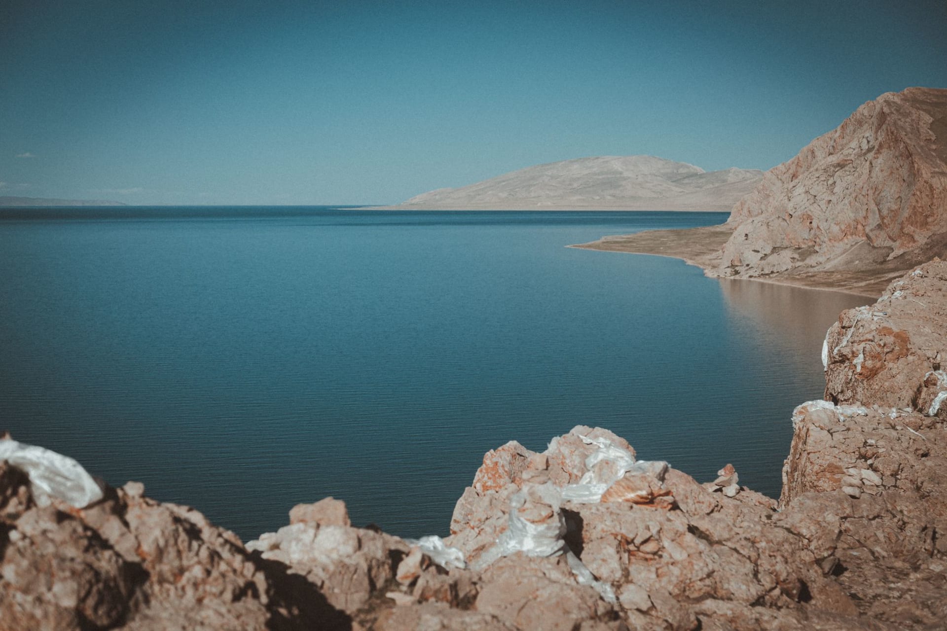 Namtso Lake's vivid turquoise water stretching to the Nyenchen Tanglha mountain range under a vast cloudless sky