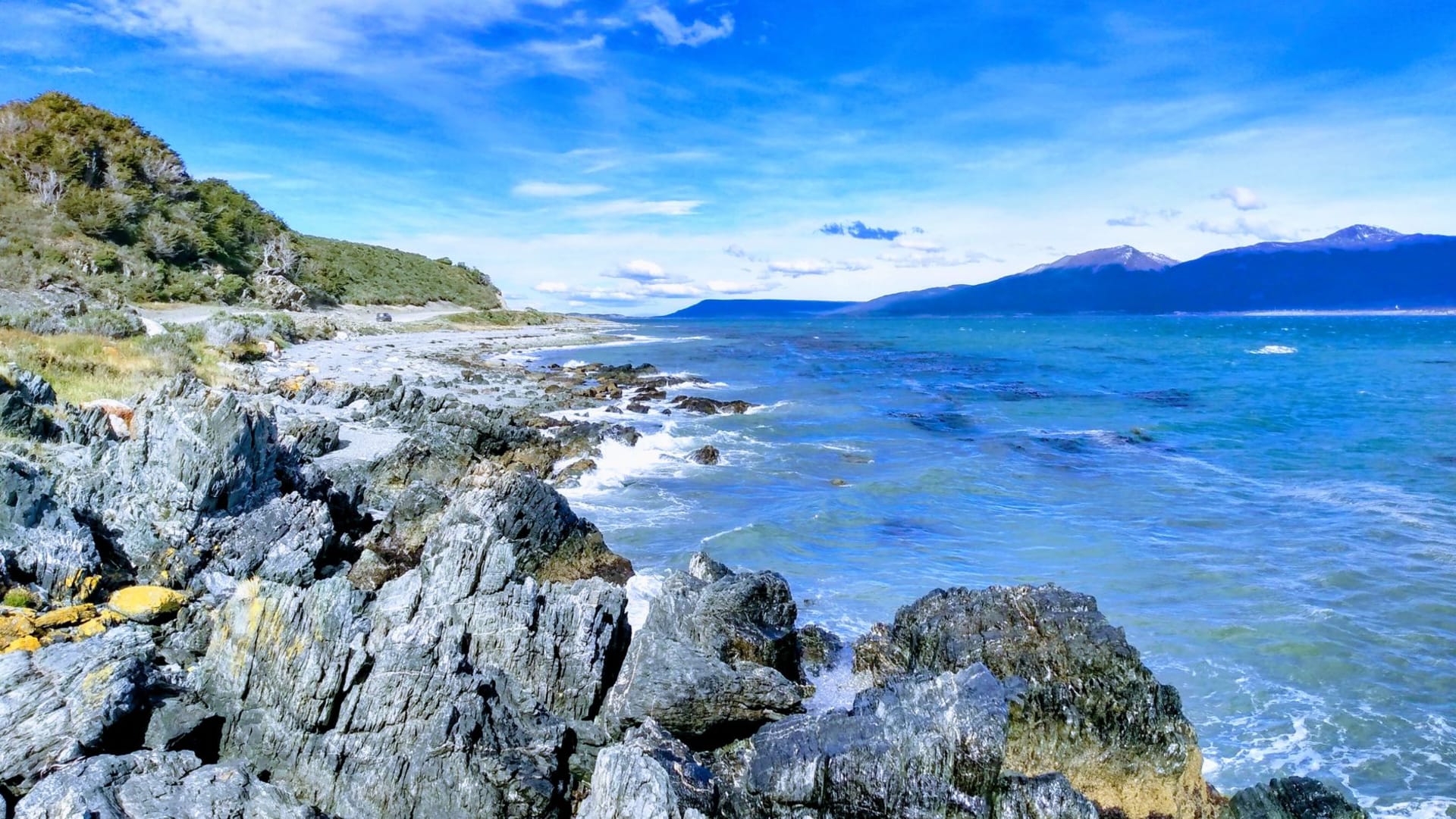 The Río Grande estuary at low tide with the wide Patagonian steppe stretching to the horizon under an enormous clouded Atlantic sky