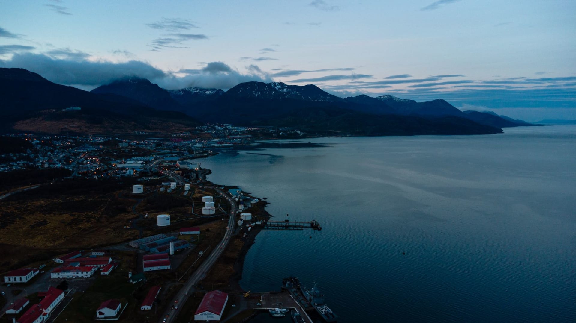 Aerial view of Ushuaia, Argentina at twilight, with mountain peaks and the Beagle Channel glowing under fading light