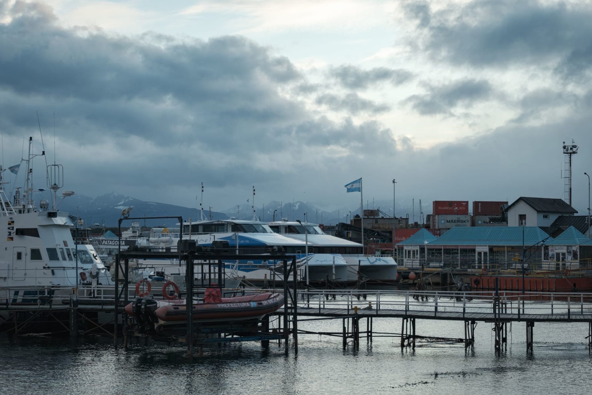 The long grey expanse of Lago Fagnano near Tolhuin in Tierra del Fuego, ringed by low forested mountains under a heavy sky