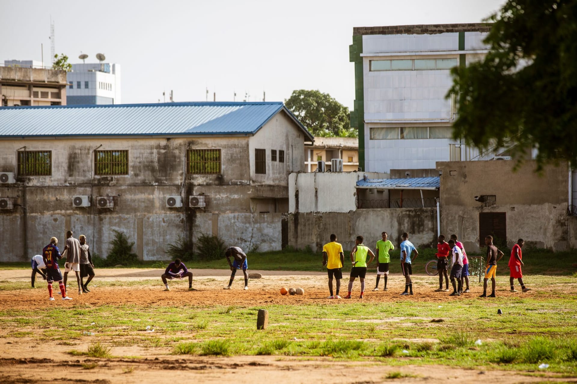 El Grand Marché de Lomé a la hora dorada, comerciantes de telas acomodando rollos de tela estampada bajo techos de láminas corrugadas