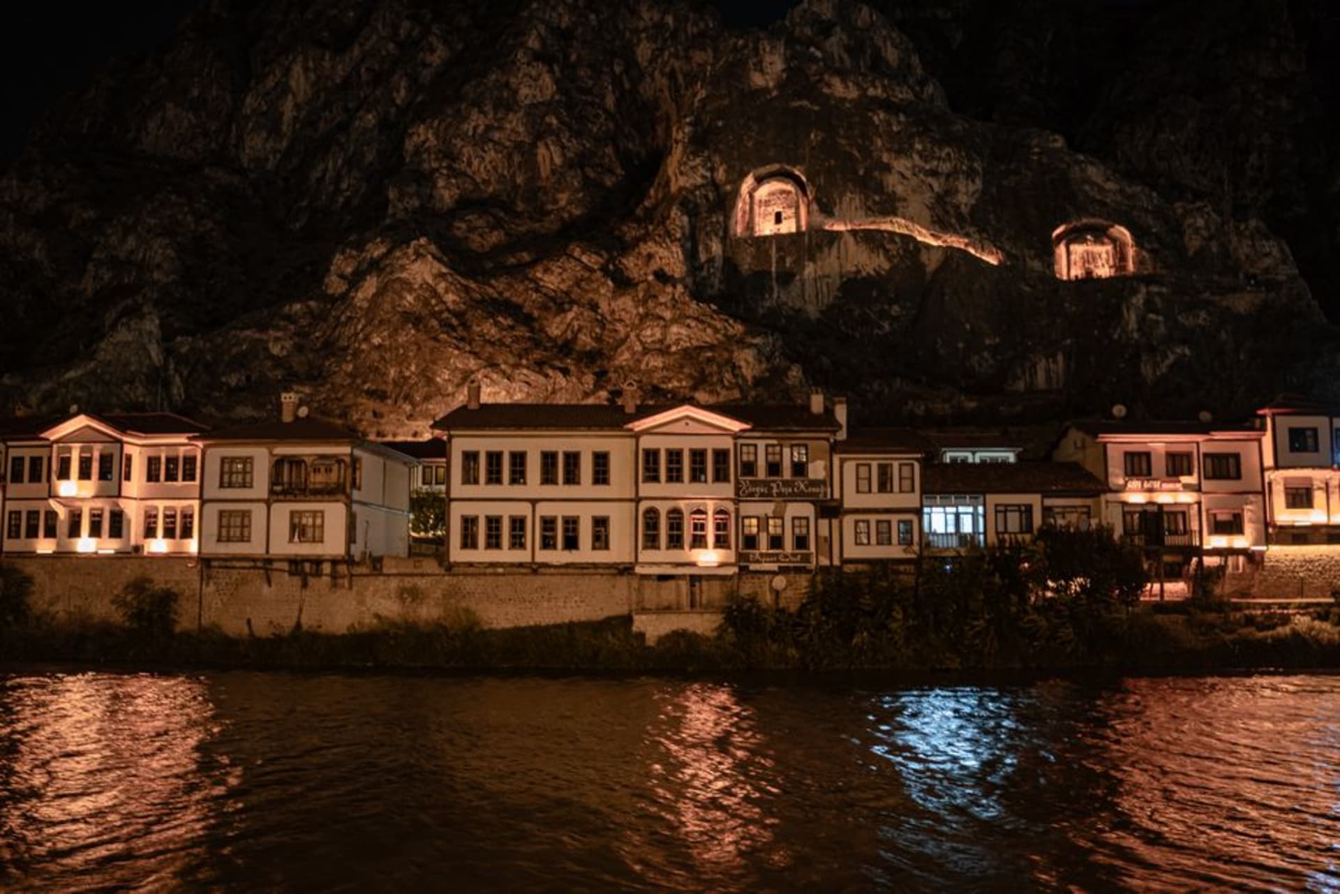 Ottoman-era timber houses lining the banks of the Yesilirmak river in Amasya, with rock-cut tombs visible in the cliffs above