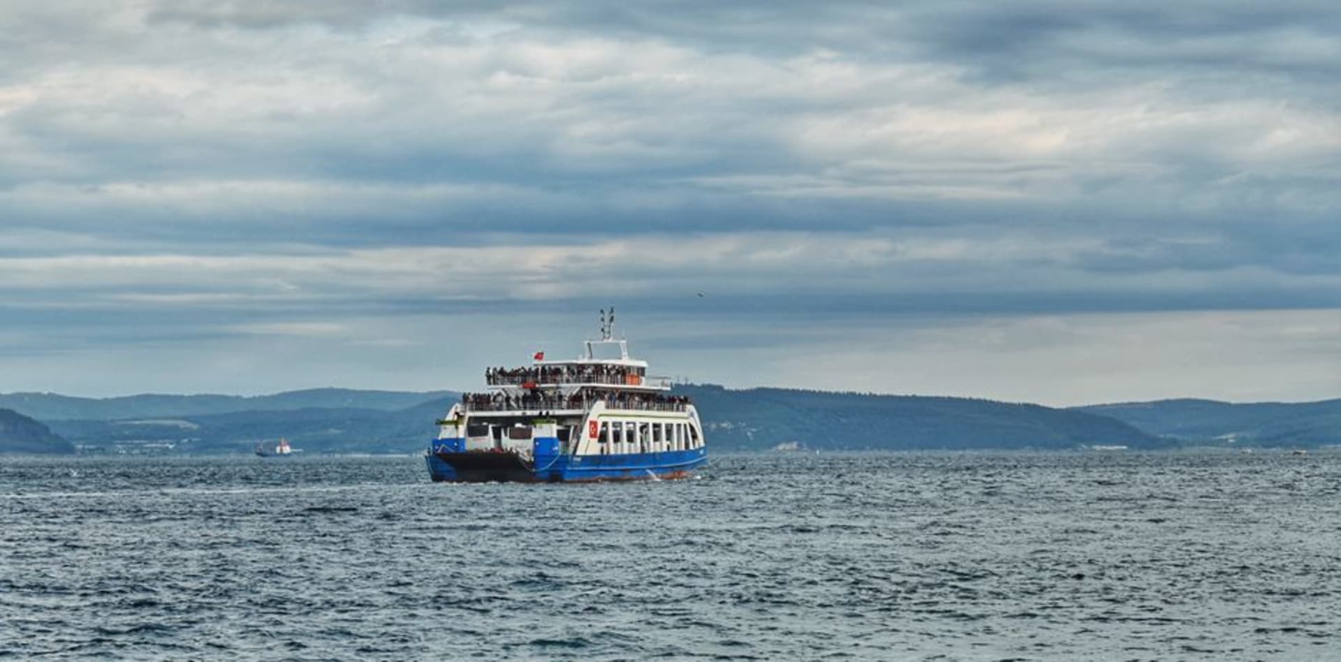 The waterfront promenade of Çanakkale along the Dardanelles at dusk with ferries crossing the strait