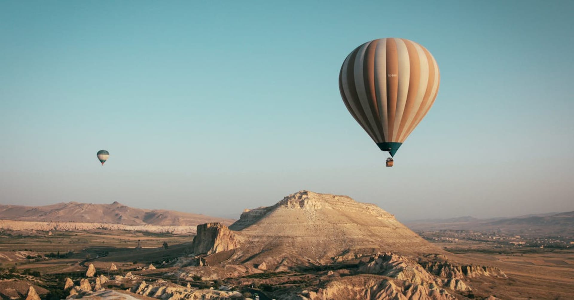 Dozens of hot air balloons floating over the fairy chimneys of Cappadocia at sunrise
