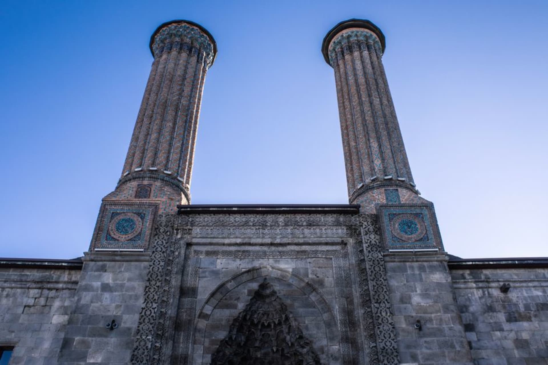 The twin minarets of the Cifte Minareli Medrese in Erzurum against a cold blue eastern Anatolian sky