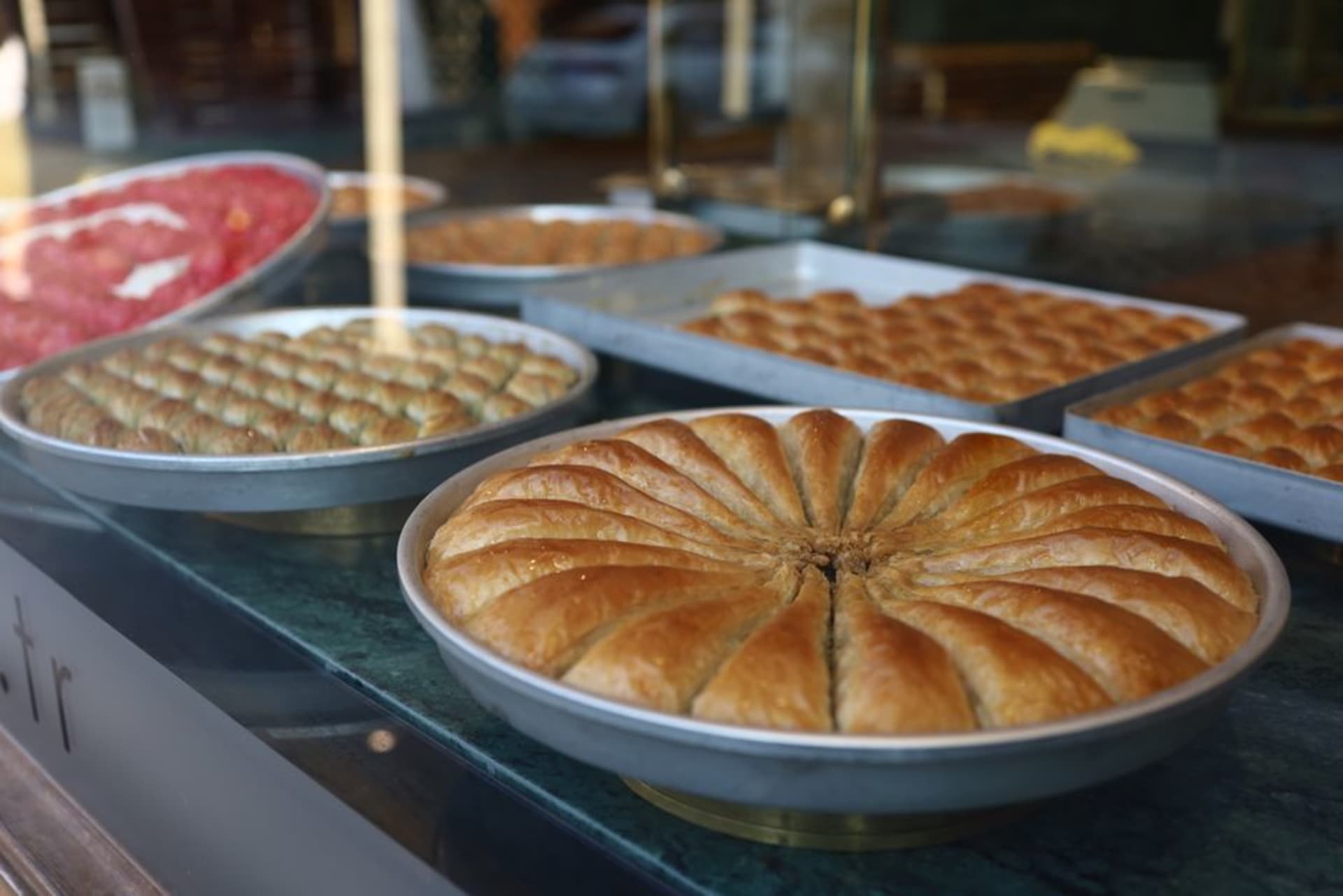 Trays of golden pistachio baklava stacked in a Gaziantep sweet shop window