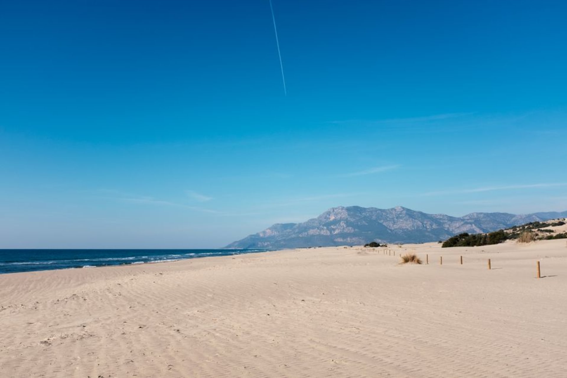 The vast, undeveloped sweep of Patara beach with dunes and empty sand stretching toward distant mountains