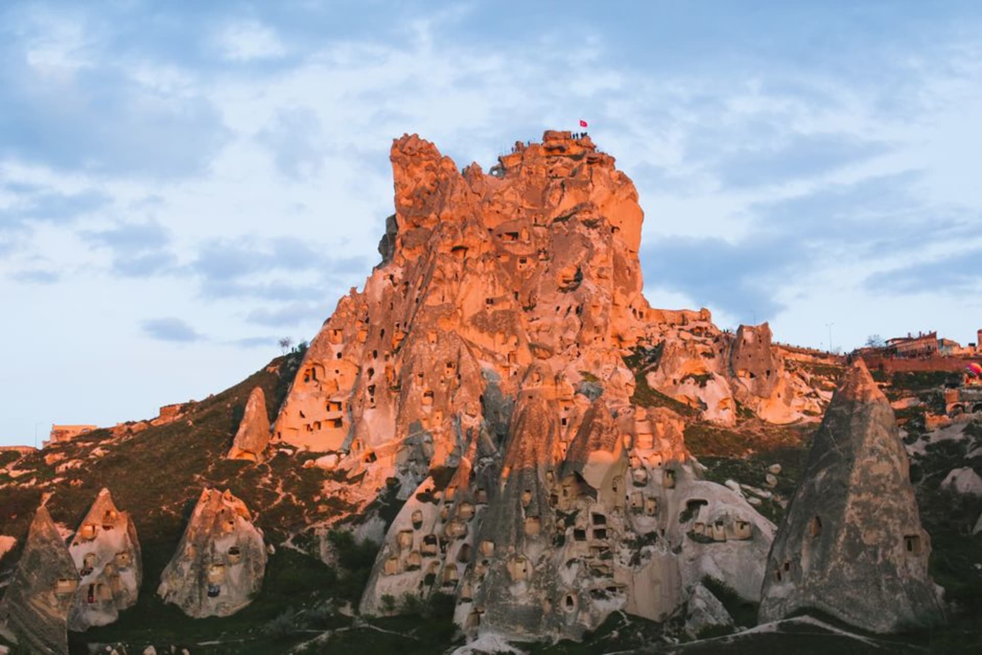 La citadelle rocheuse imposante d'Uçhisar criblée de fenêtres et de portes sculptées, s'élevant au-dessus de la vallée cappadocienne au coucher du soleil