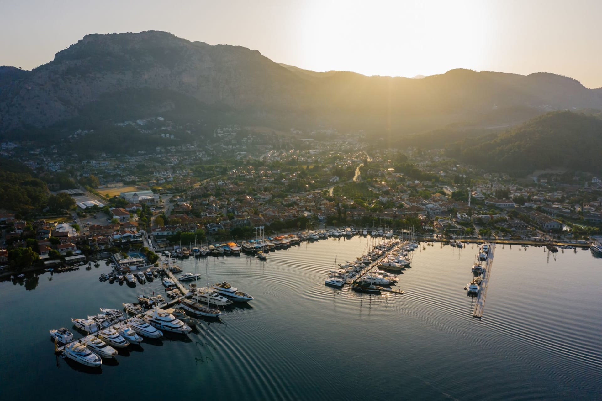 Göcek bay at early morning, masts of gulets and sailboats reflected in glassy water, pine-forested hills rising behind
