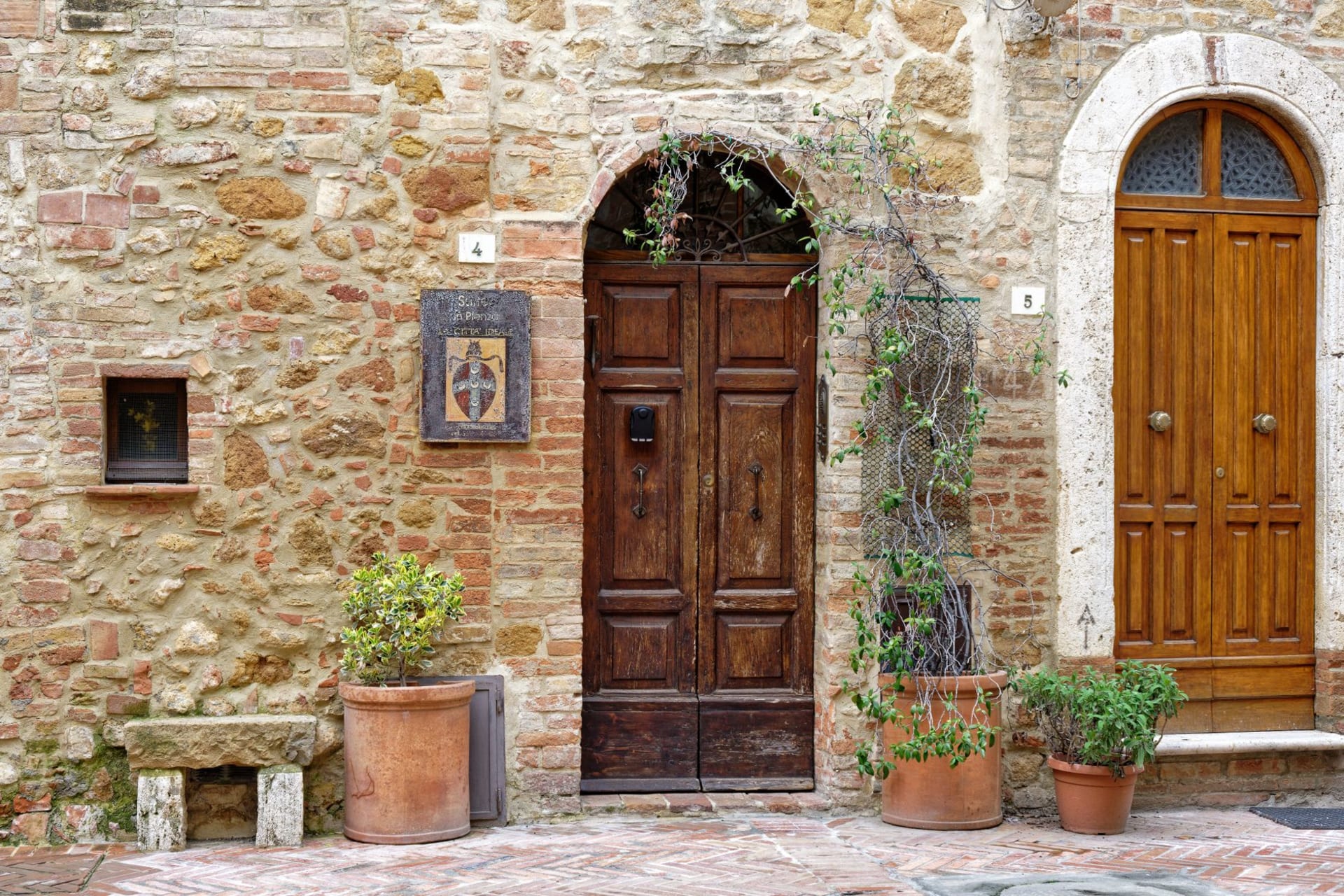 Le duomo et la façade du palais de Pienza donnant sur la place principale, les collines ondulantes du Val d'Orcia visibles par une trouée entre les bâtiments à l'arrière