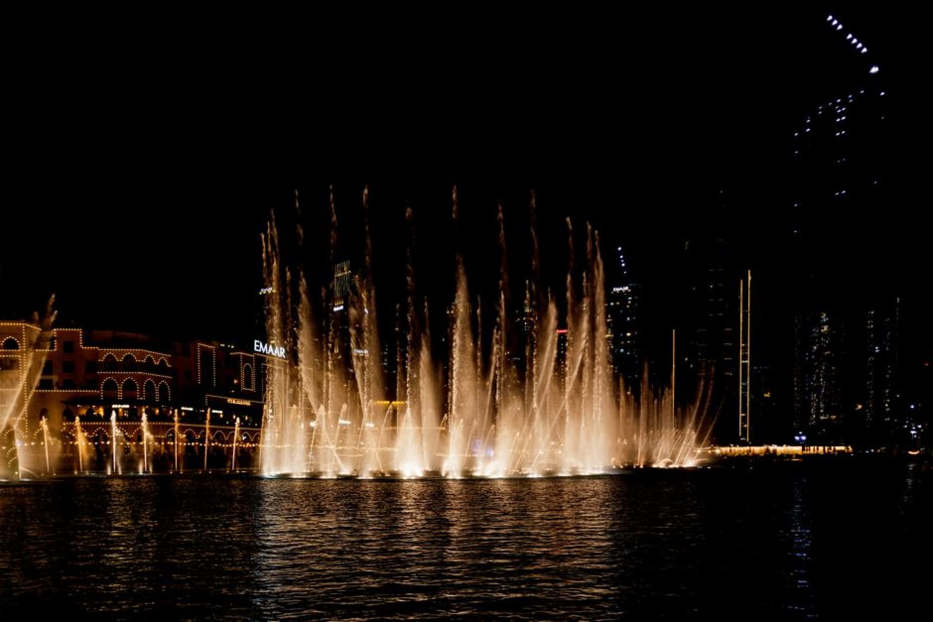 Dubai Fountain shooting illuminated water jets high into the night sky in front of Burj Khalifa
