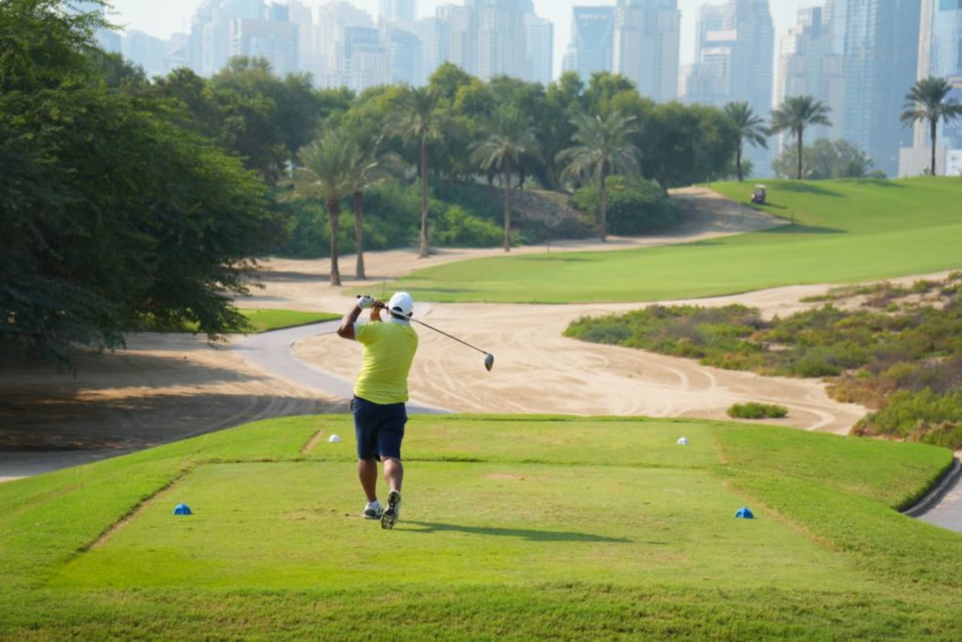 Manicured golf course and green parkland with Dubai Hills villas in the background