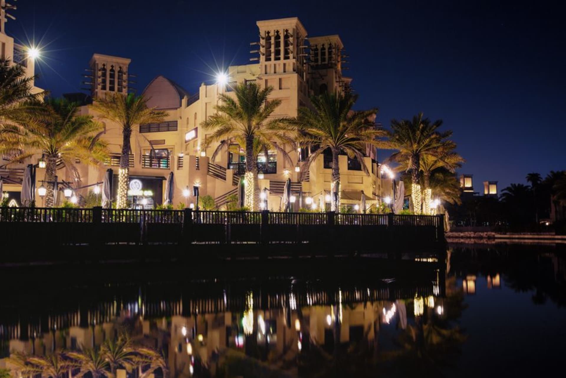 Jumeirah Mosque illuminated at night with its Fatimid-style domes and minarets glowing against the dark sky