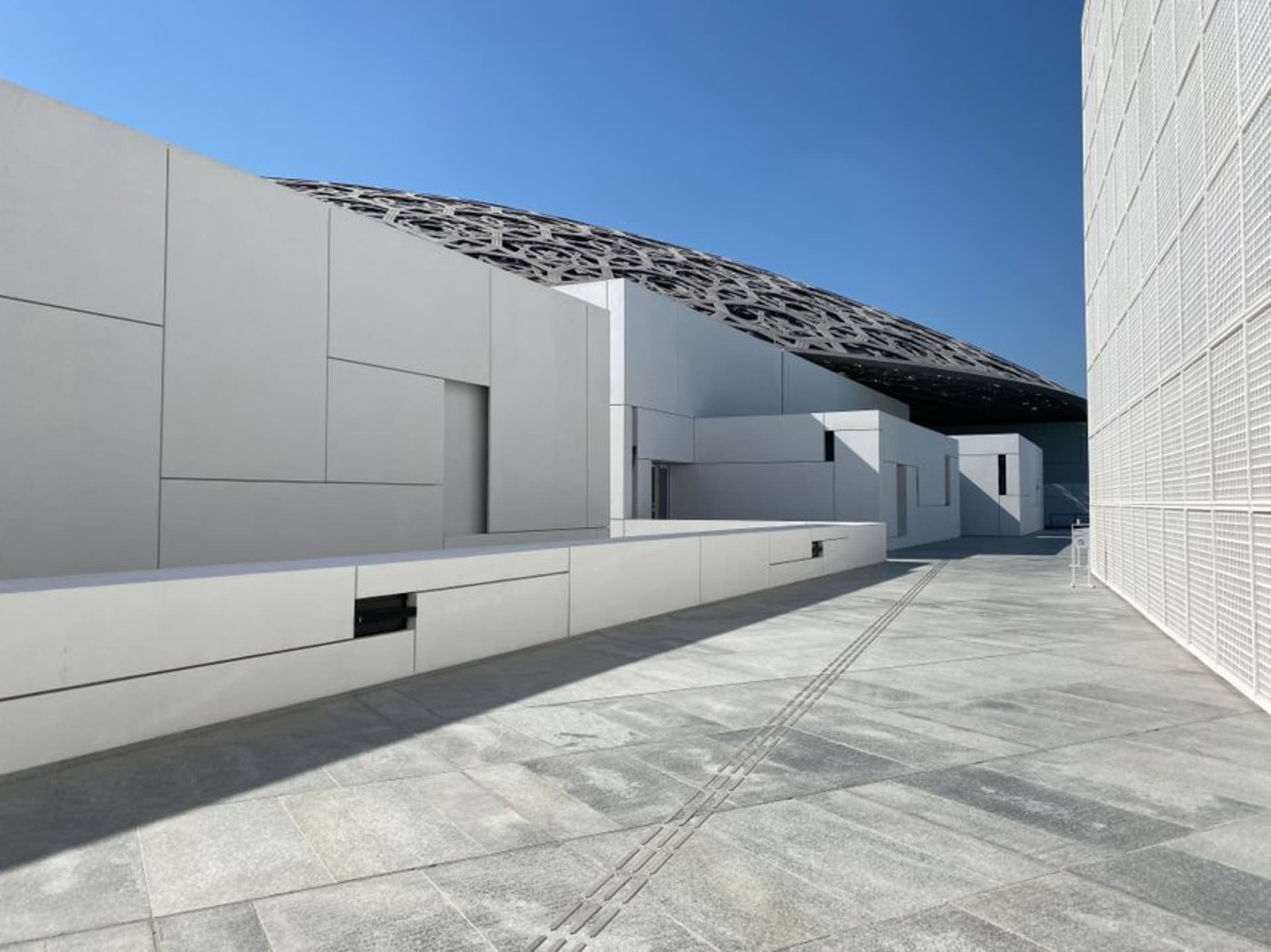Sunlight filtering through the perforated dome of the Louvre Abu Dhabi onto the museum plaza below