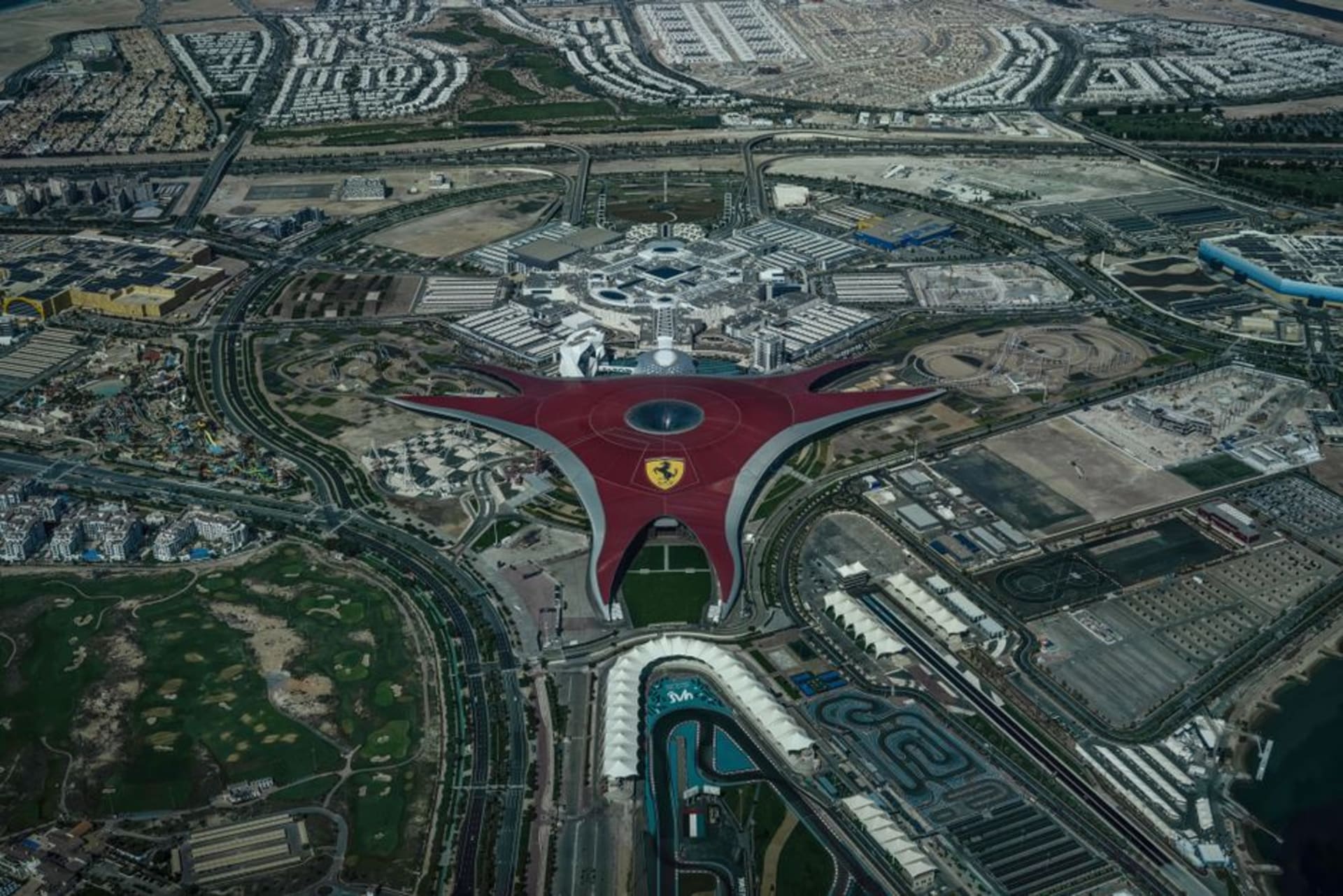 La structure rouge de Ferrari World aux côtés des tribunes du circuit de Yas Marina au crépuscule sur l'île de Yas