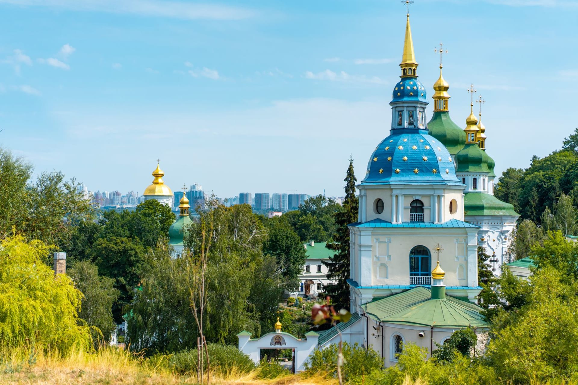 Khotyn Fortress viewed from across the Dniester River, its five towers and curtain wall reflected in the slow green water, the cliff face dropping sheer below the walls
