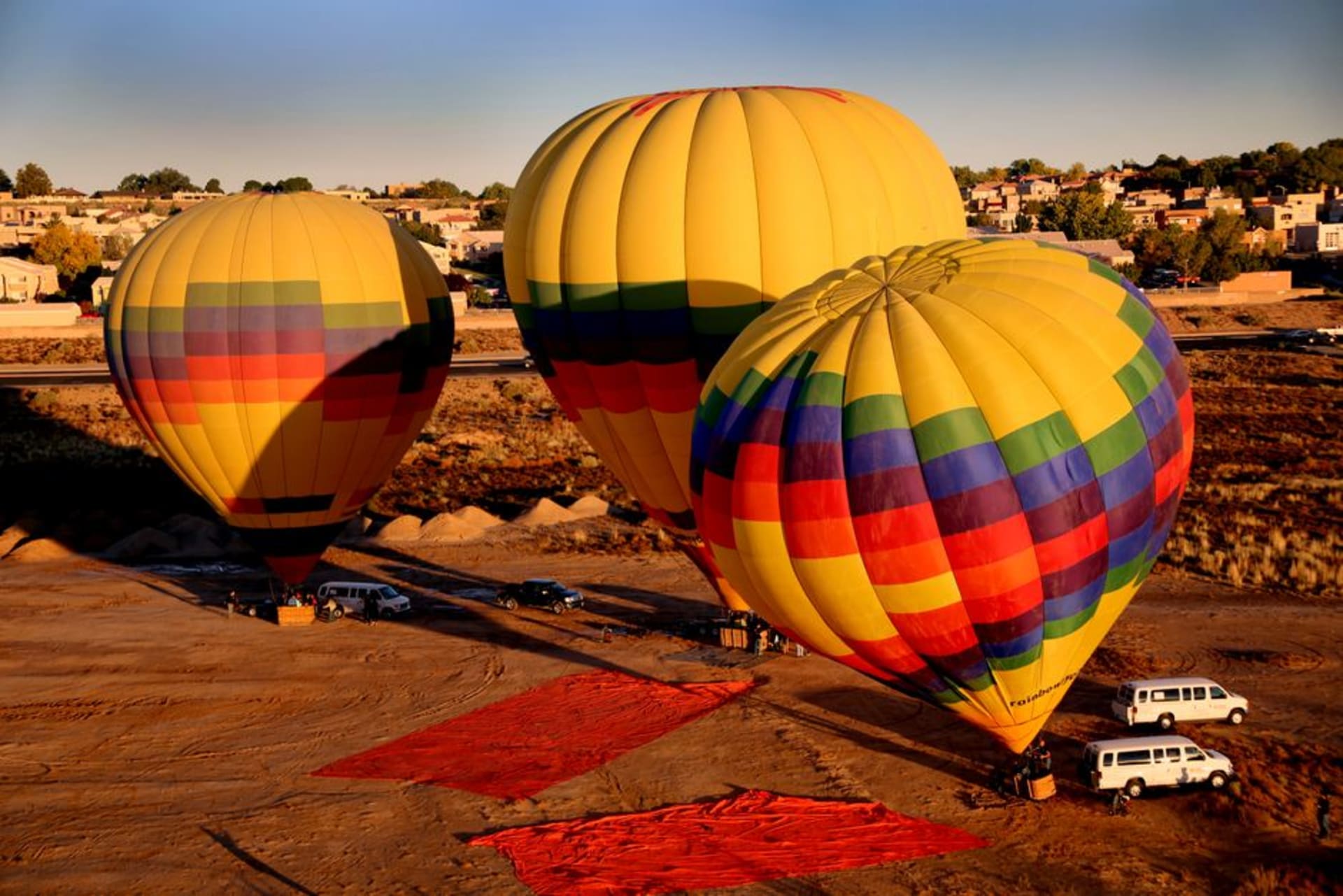 Dozens of colourful hot-air balloons rising over Albuquerque with the Sandia Mountains behind at sunrise