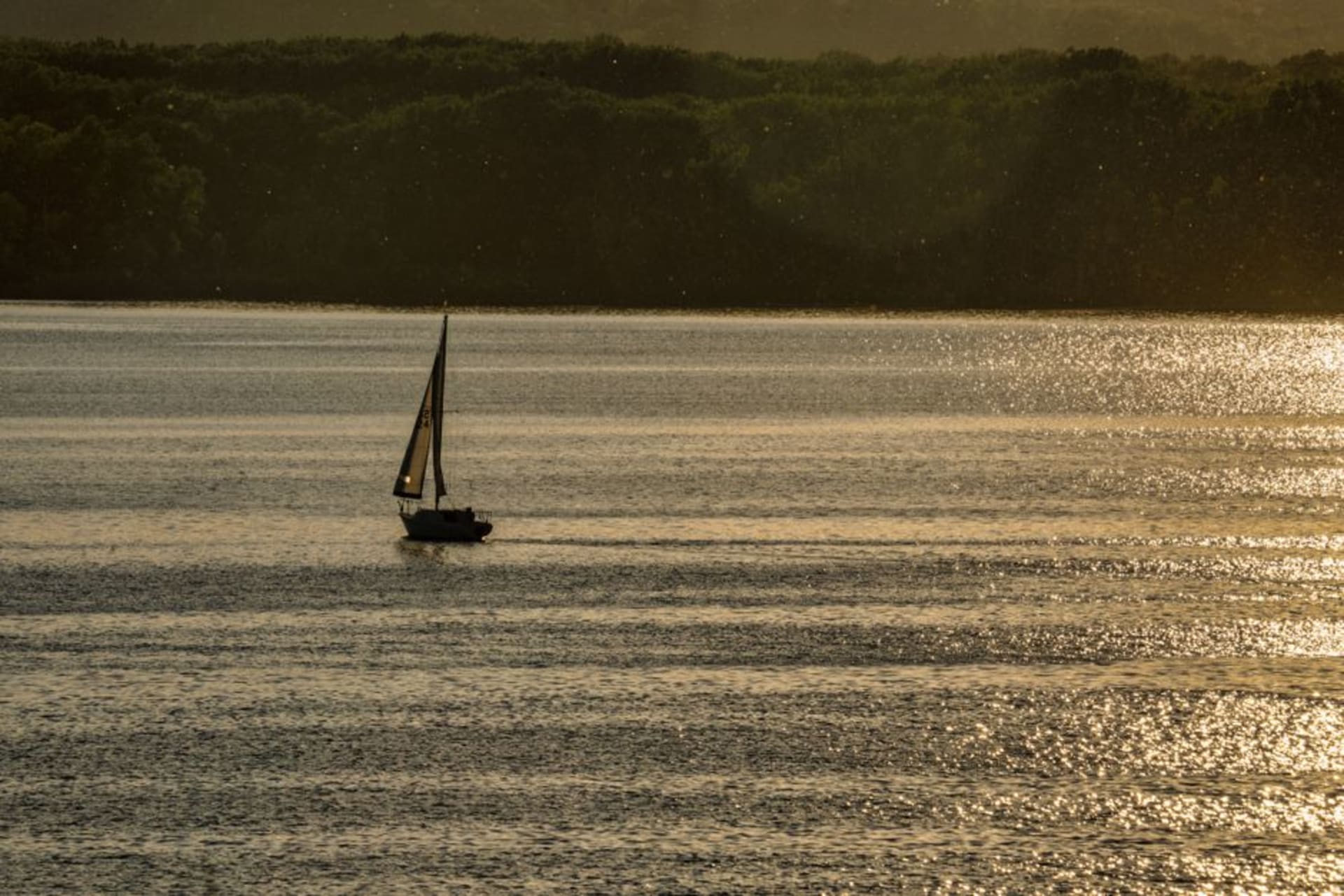 Sailboats on Clear Lake at sunset with the town shoreline in Iowa