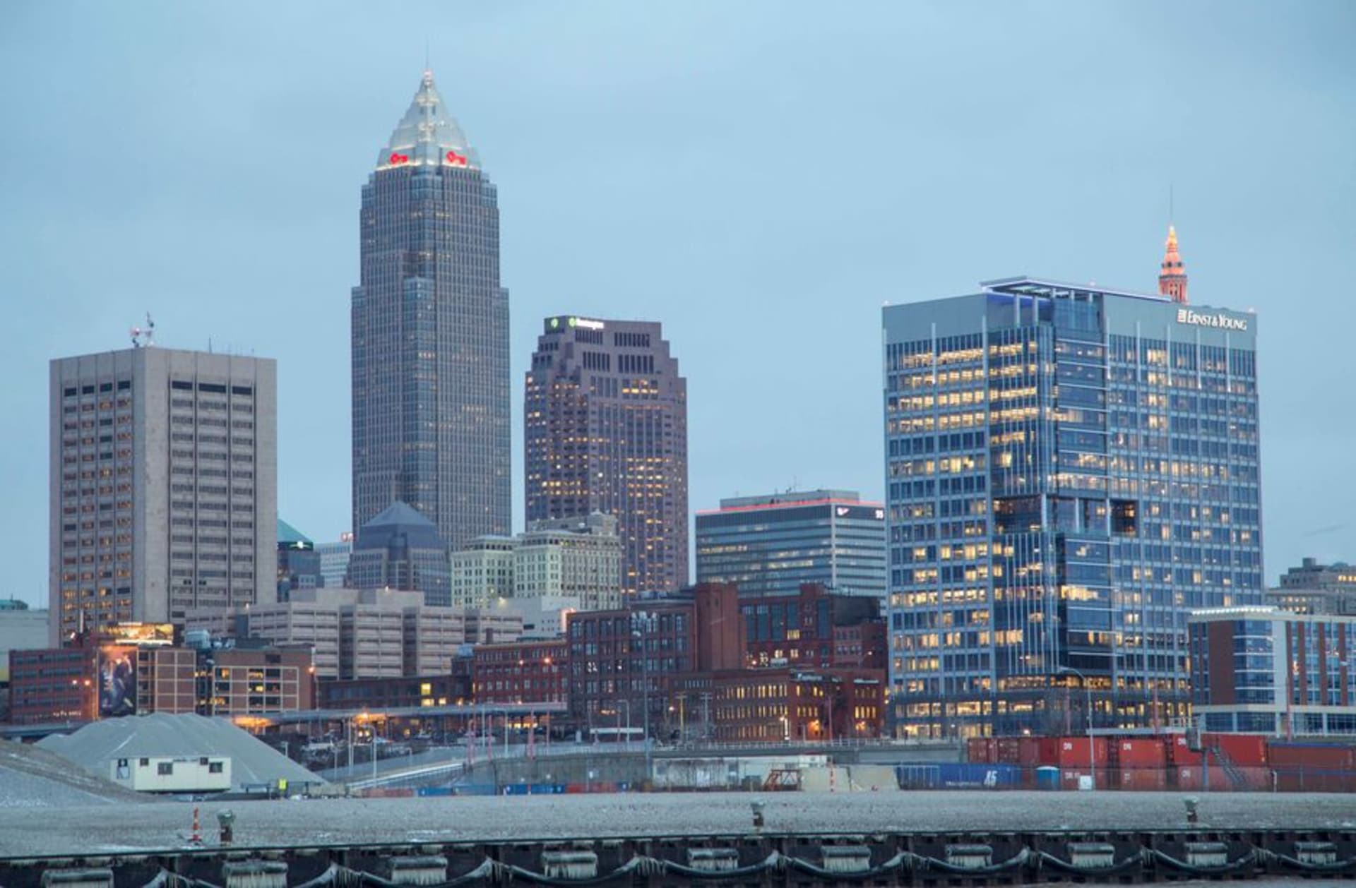 The Cleveland skyline along the Lake Erie waterfront at dusk with the glass pyramid of the Rock and Roll Hall of Fame in the foreground.