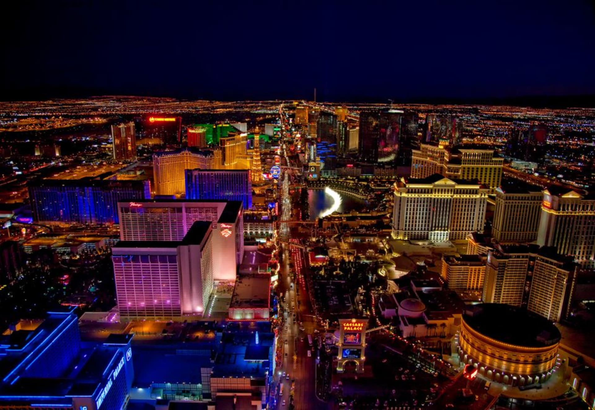 The glowing Las Vegas Strip at dusk with the fountains of the Bellagio and neon hotel towers stretching into the desert night
