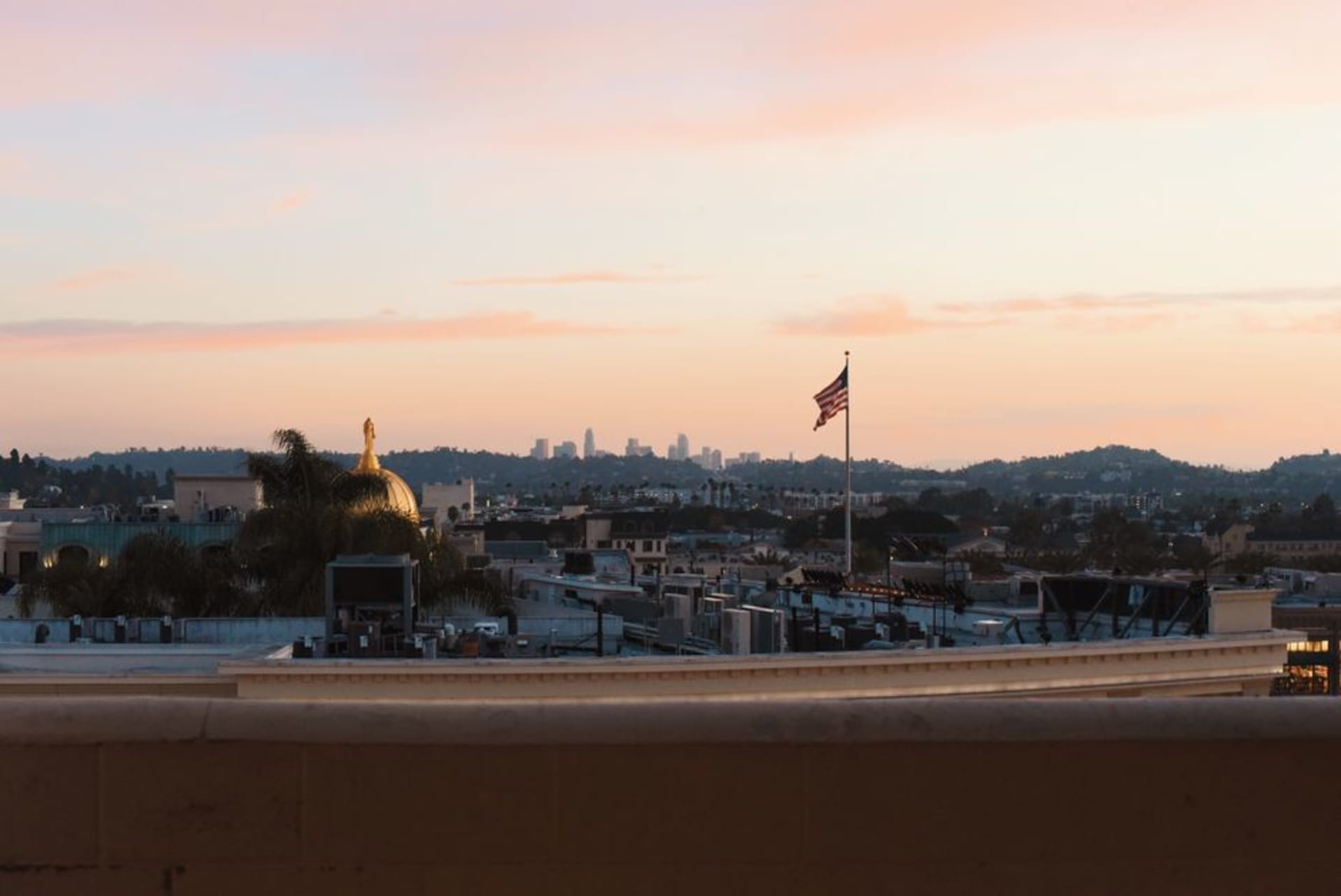 The Los Angeles skyline and Hollywood hills under a hazy golden afternoon light