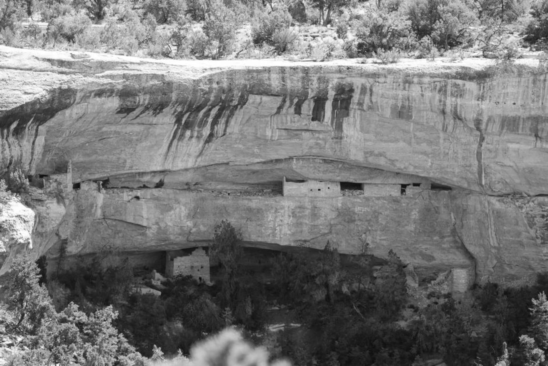 Ancient stone cliff dwelling set into a large sandstone alcove in a canyon wall