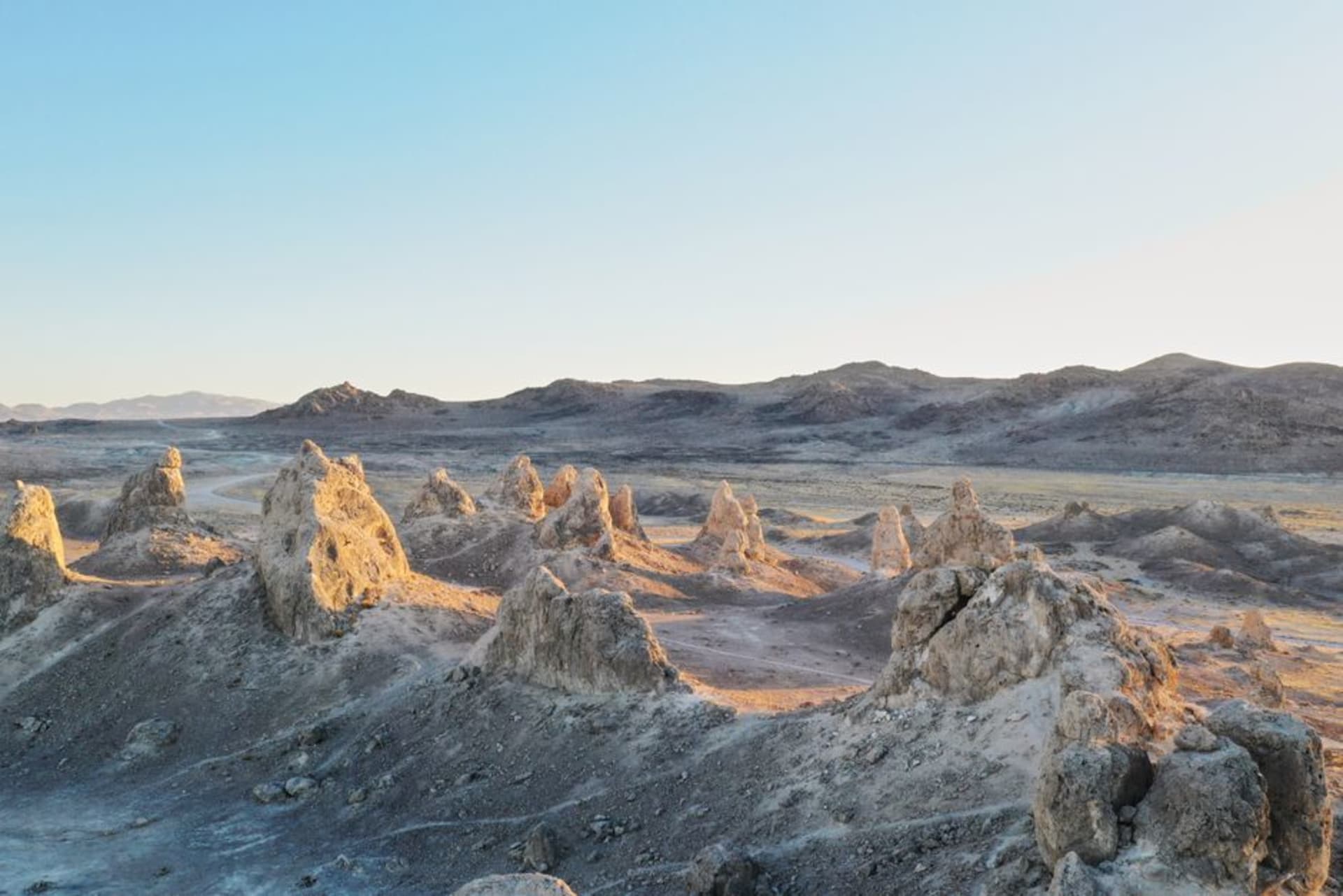 Jagged volcanic rock spires rising above dry golden hillsides and chaparral