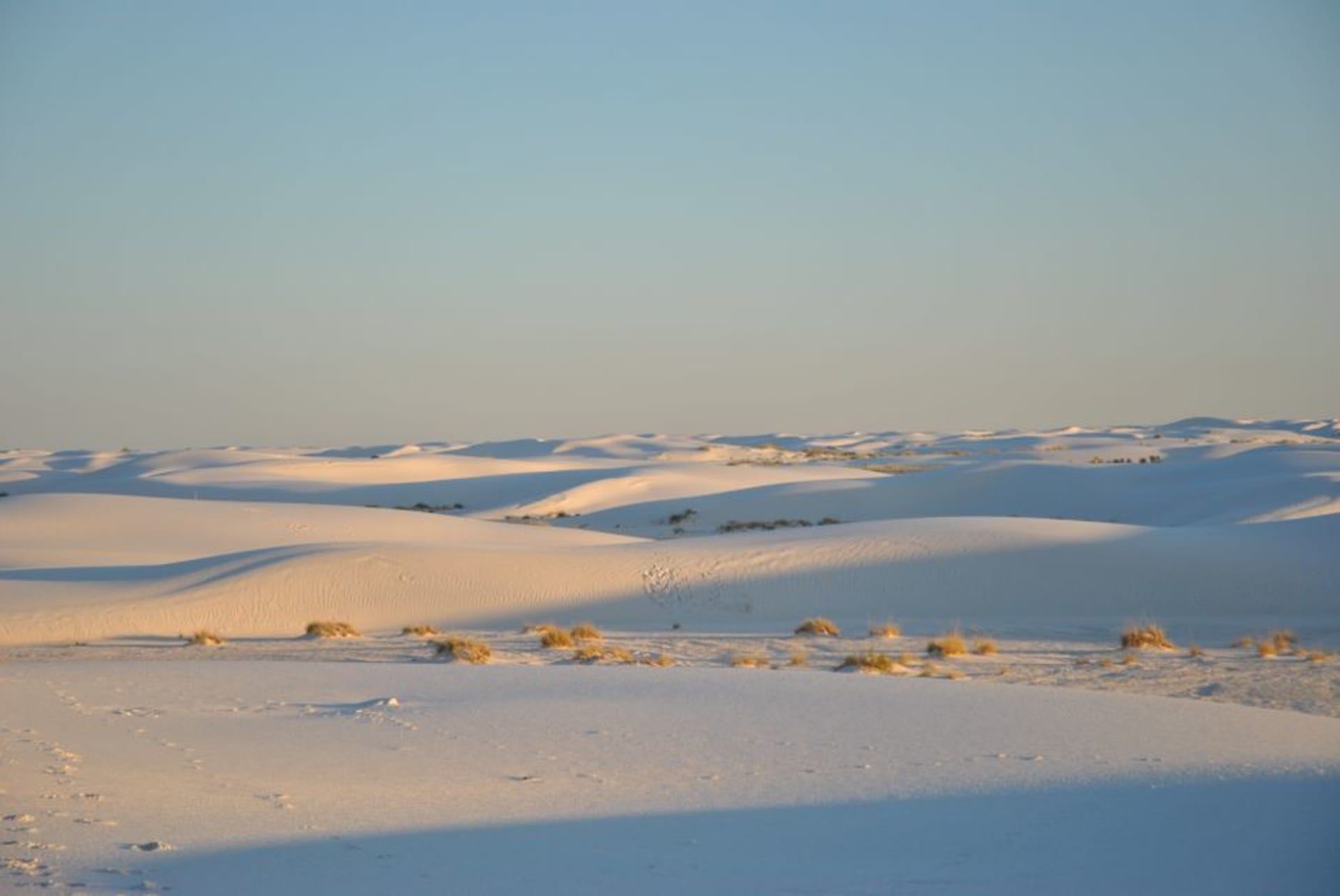 Rippled white gypsum dunes stretching to distant blue mountains under a wide sky