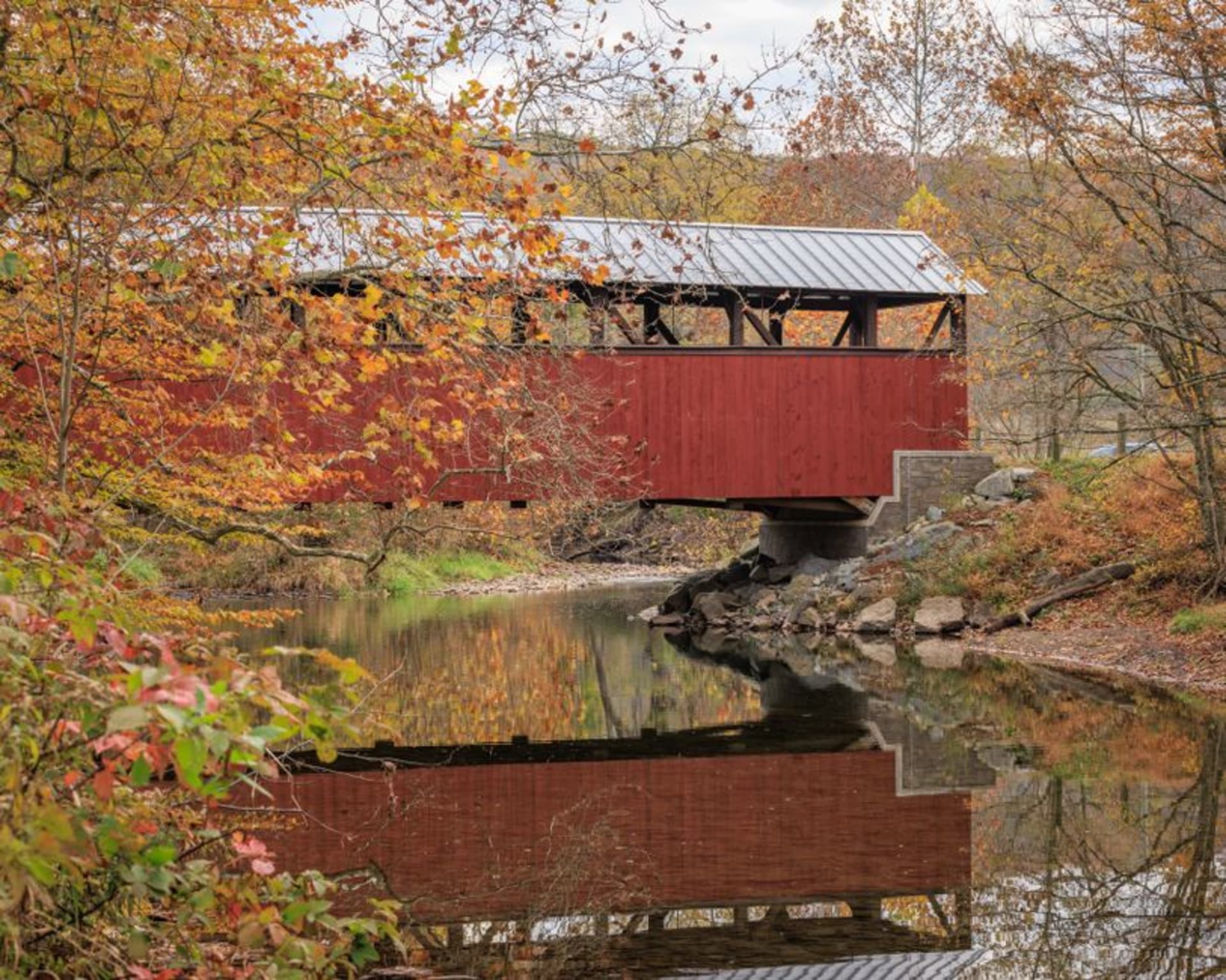 A red covered bridge over a creek in the countryside near Winterset, Iowa