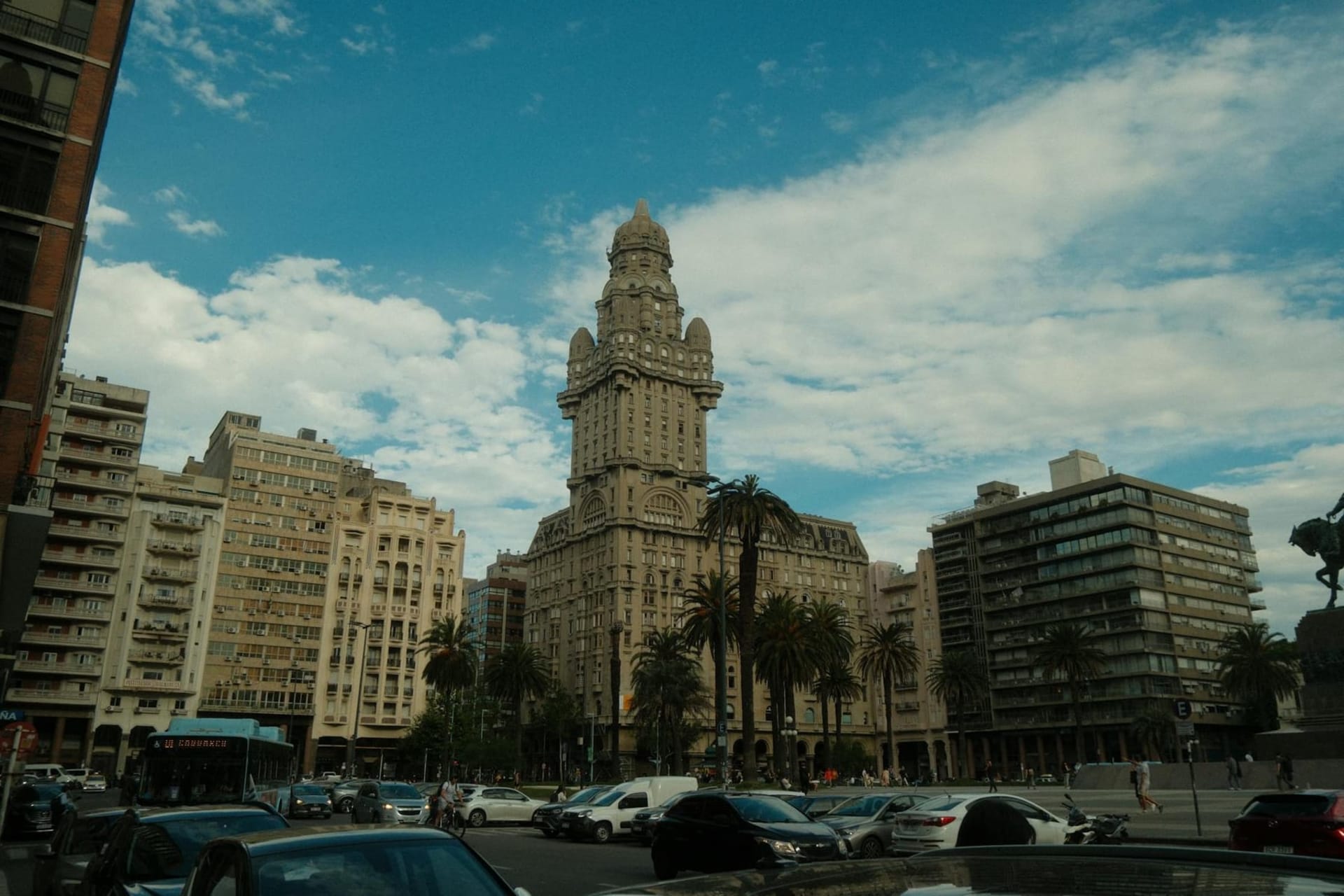 The Rambla of Montevideo stretching along the Río de la Plata at golden hour, with locals sitting on the stone seawall and the Ciudad Vieja skyline in the distance