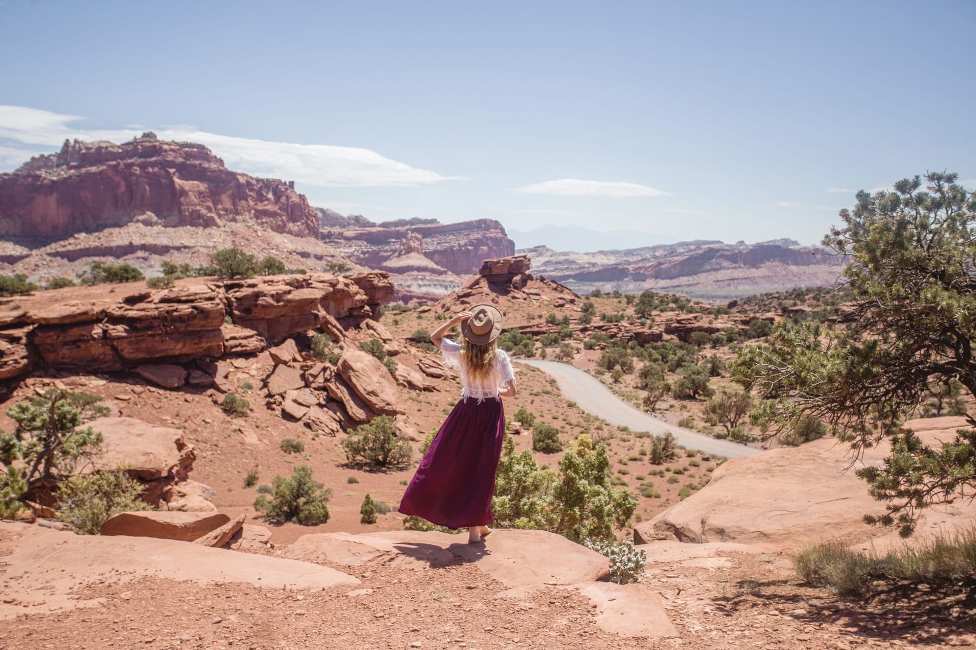 Layered red and white sandstone cliffs receding into a wide desert basin under a hard blue sky